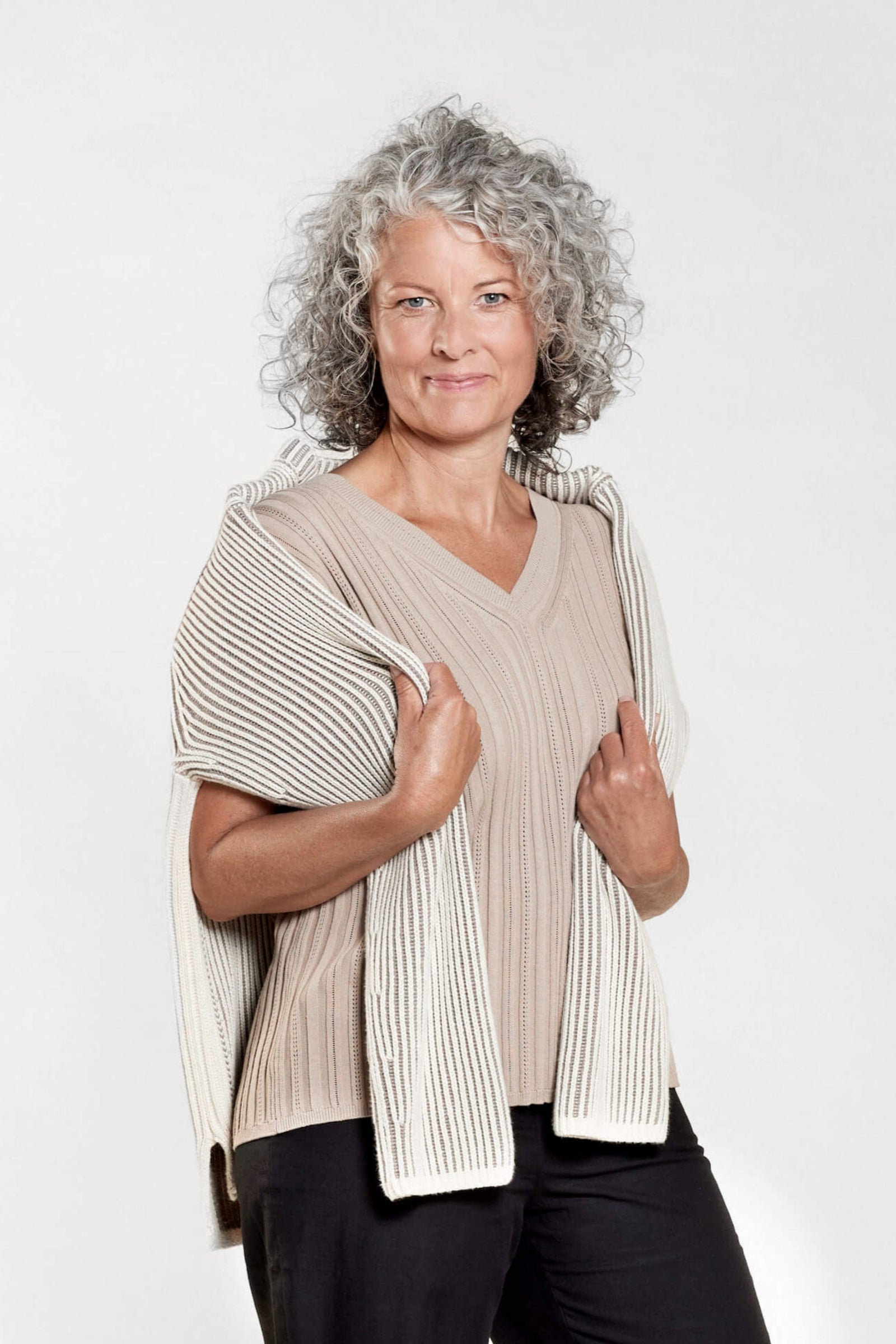 Model wears Cyme Copenhagen's coordinated taupe knit top and skirt set, showcasing the Danish brand's commitment to sustainable materials and elegant design in women's fashion, available from top fashion stores in Denmark.