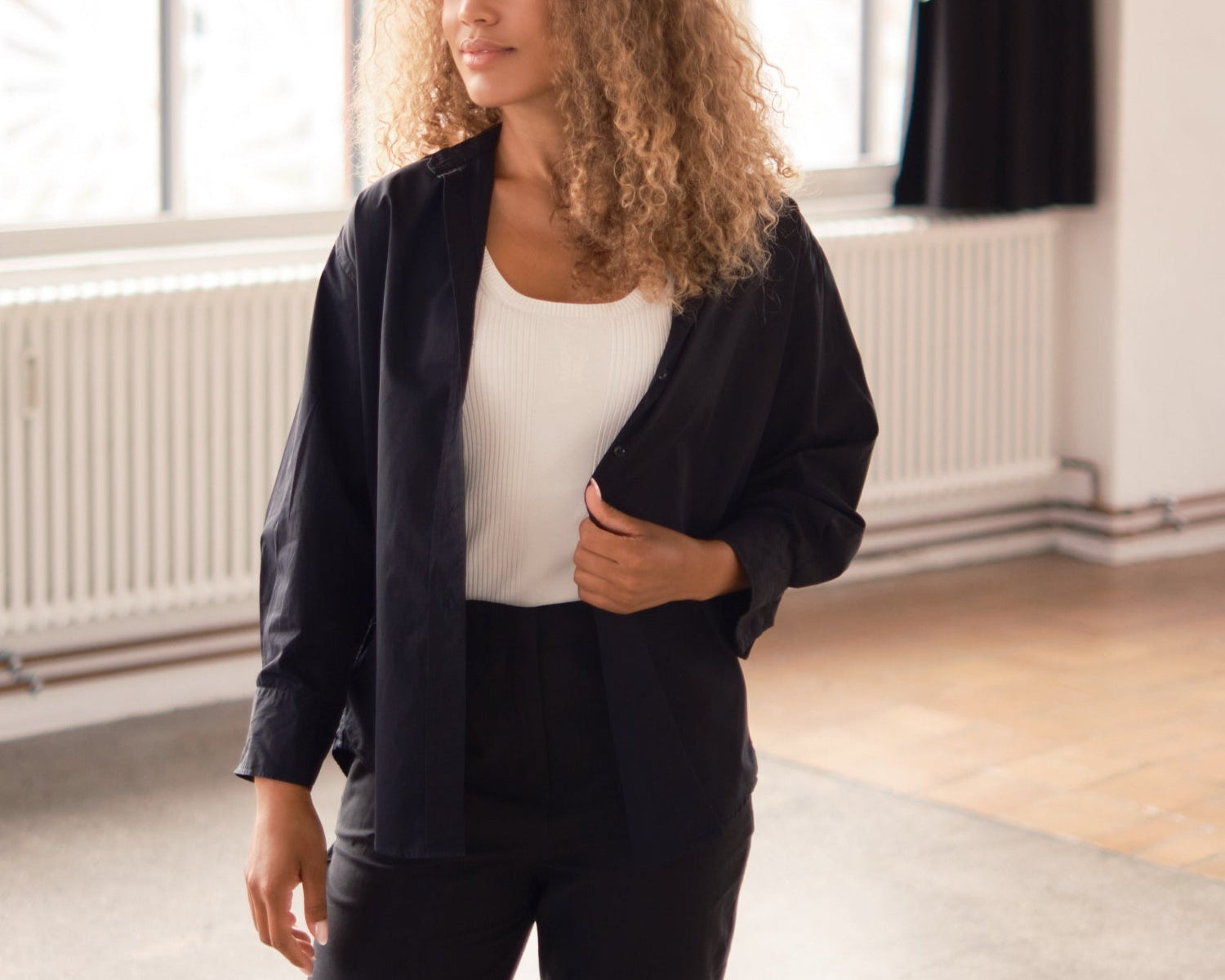 Model wearing a black shirt layered over a white top.