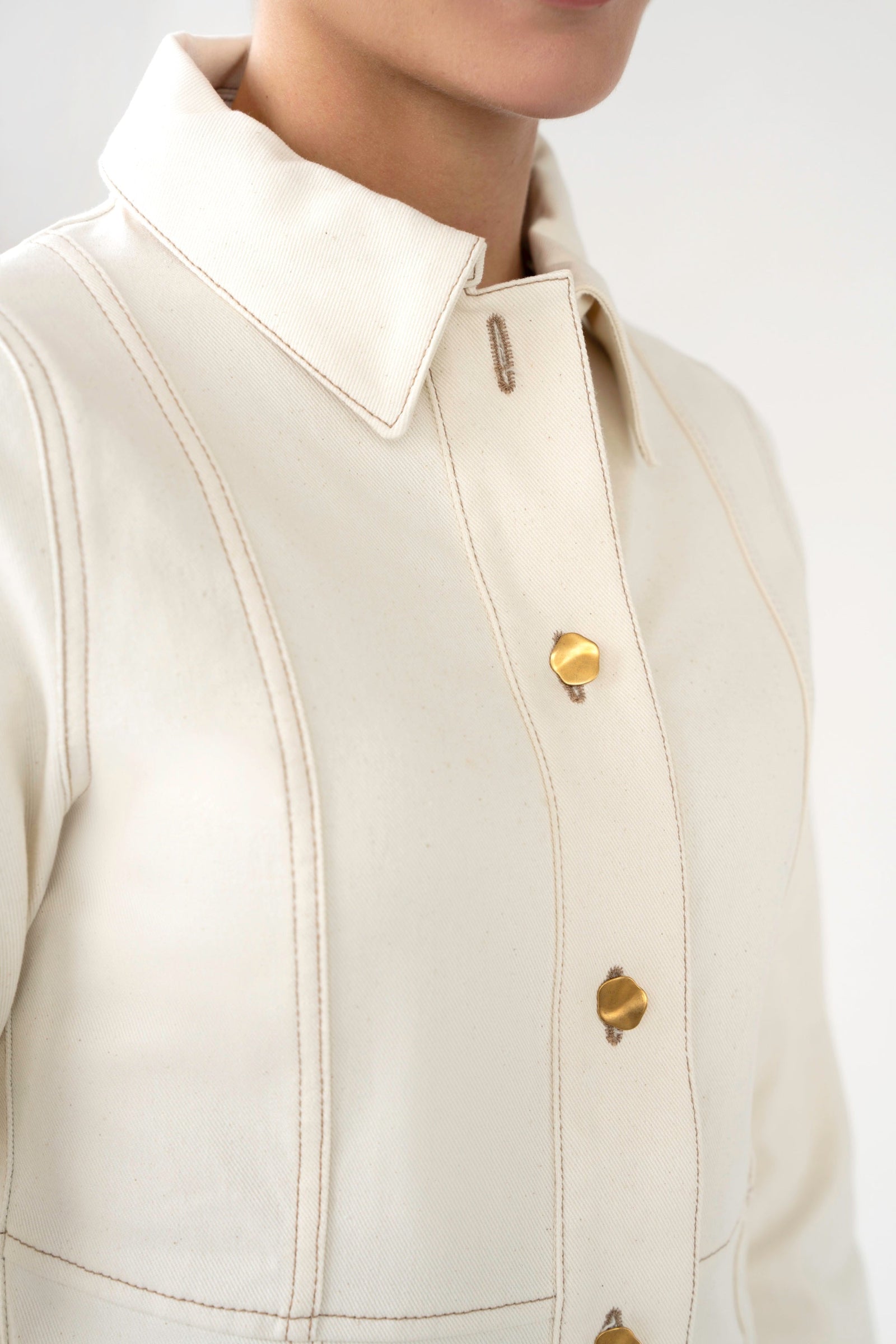 Close-up of a beige jacket with gold buttons on a white background