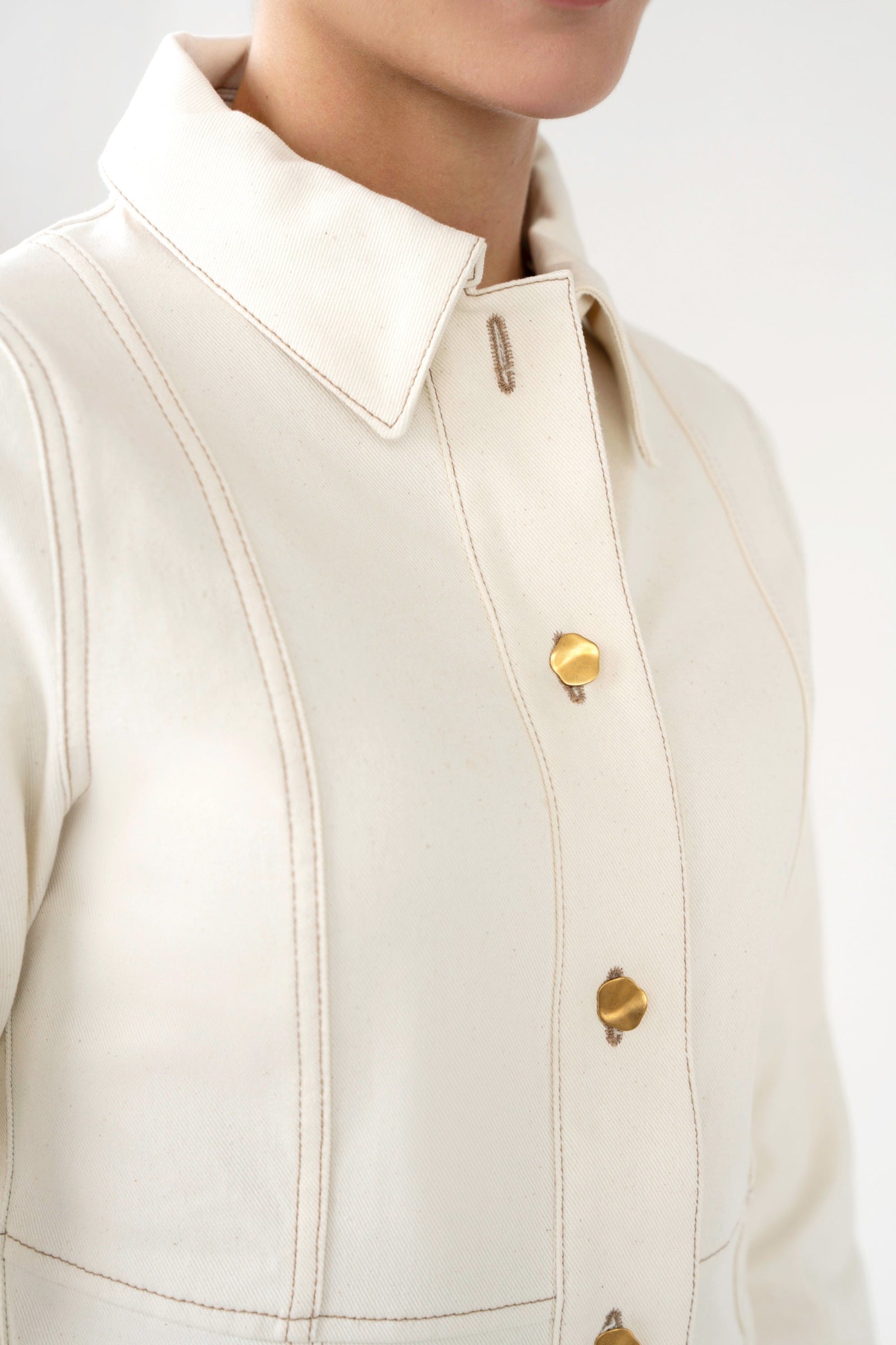 Close-up of a beige jacket with gold buttons on a white background