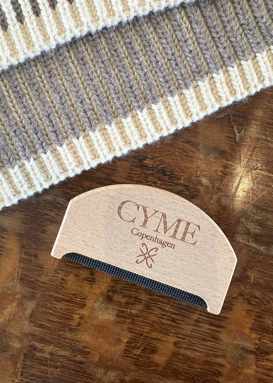 Wooden comb with 'Cyme Copenhagen' branding on a wooden surface