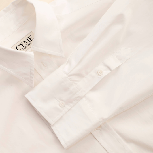 Detail of Cyme Copenhagen's white supima shirt with logo on the collar, embodying the clean and sustainable design of Scandinavian fashion.