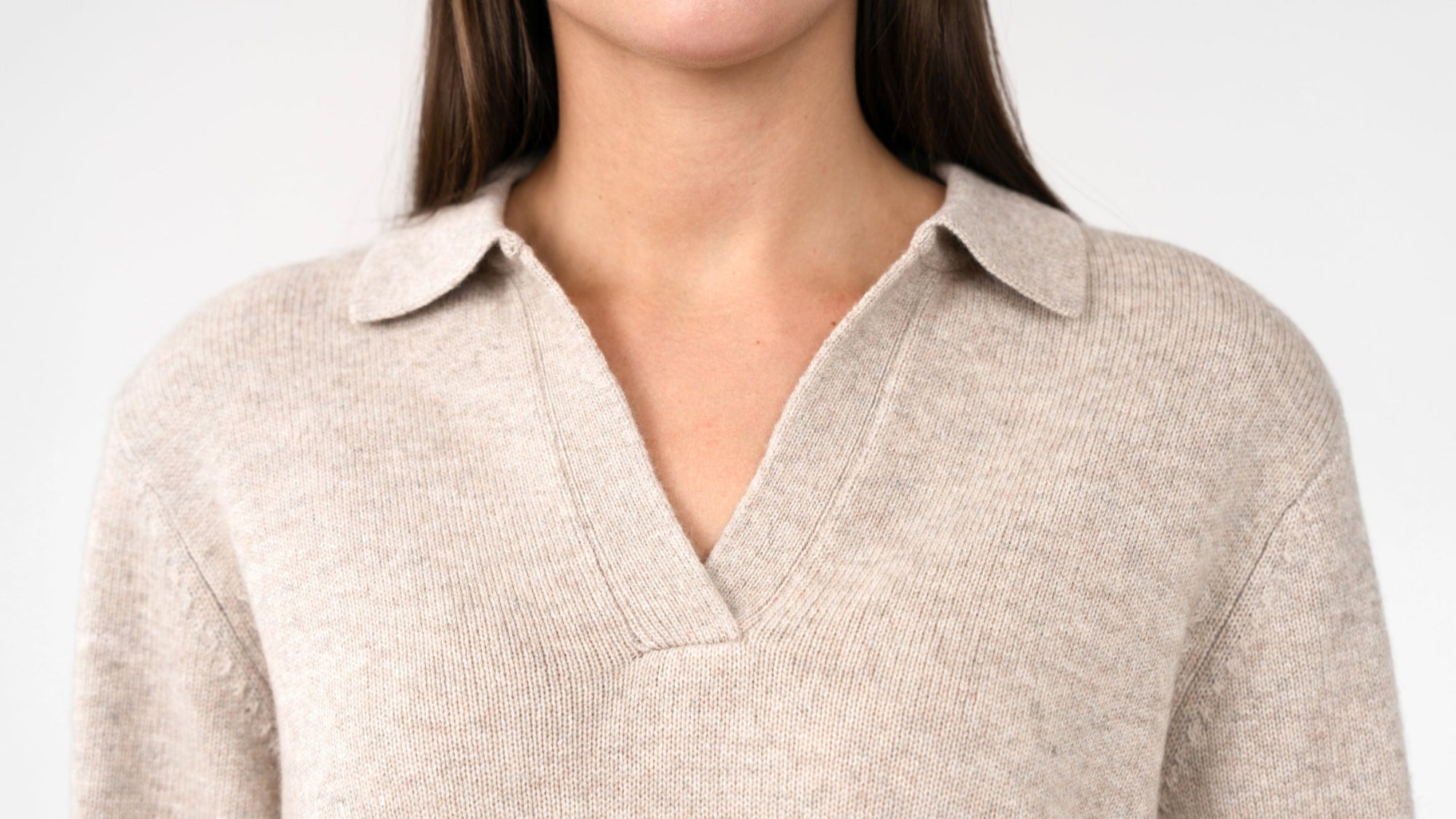A close up picture of a dark haired woman wearing a cashmere polo jumper. 