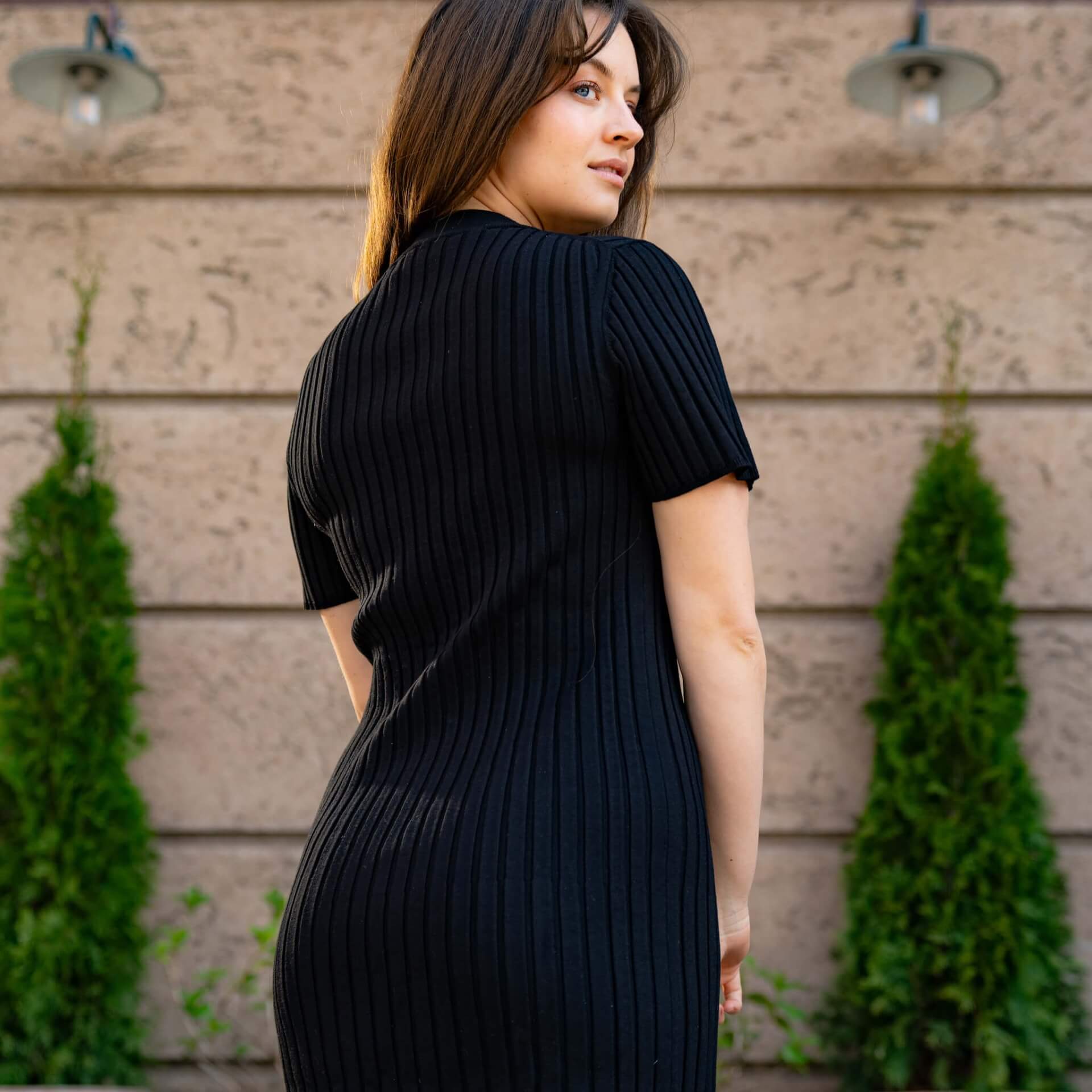 Model displaying Cyme Copenhagen's sustainable fashion line, a sleek black ribbed knit dress, embodying the elegant simplicity of Danish design available in inclusive sizes.