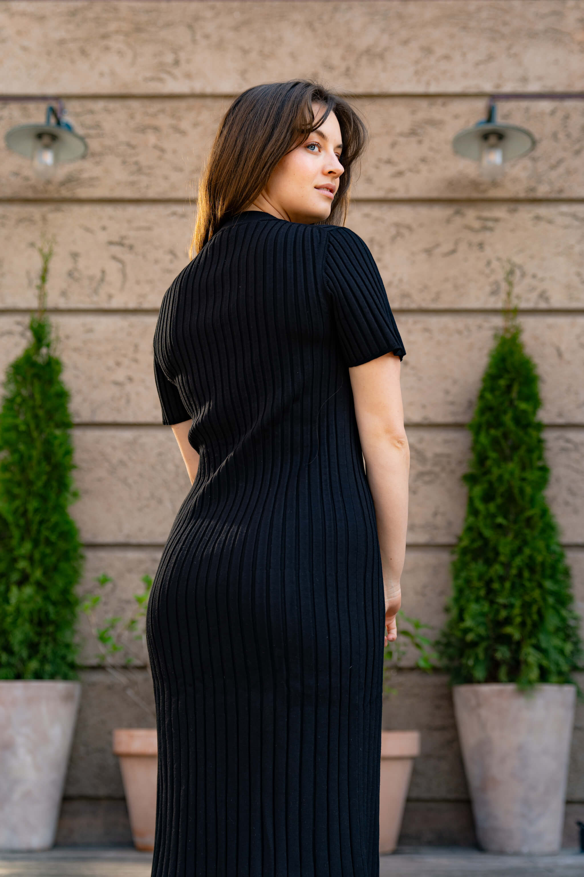 Model displaying Cyme Copenhagen's sustainable fashion line, a sleek black ribbed knit dress, embodying the elegant simplicity of Danish design available in inclusive sizes.