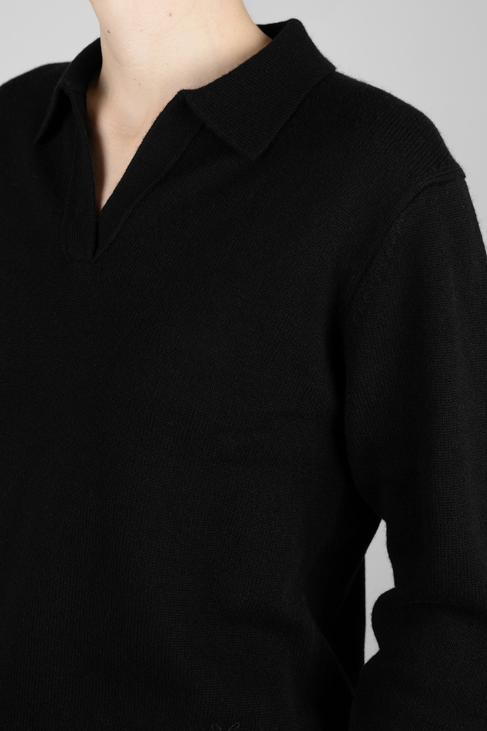 Close-up of the CYME Cashmere-Merino Polo Jumper in black, worn on-model, highlighting the open polo collar, V-neckline and soft cashmere-merino knit texture.