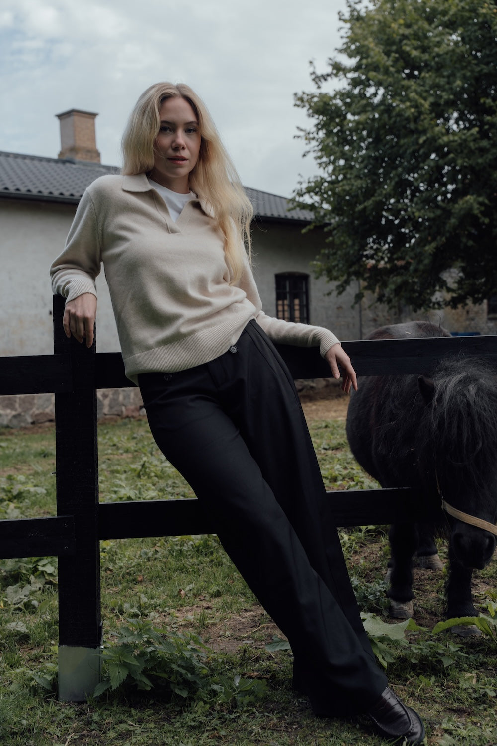 Beige Cashmere-Merino Polo Jumper worn outdoors with black trousers.