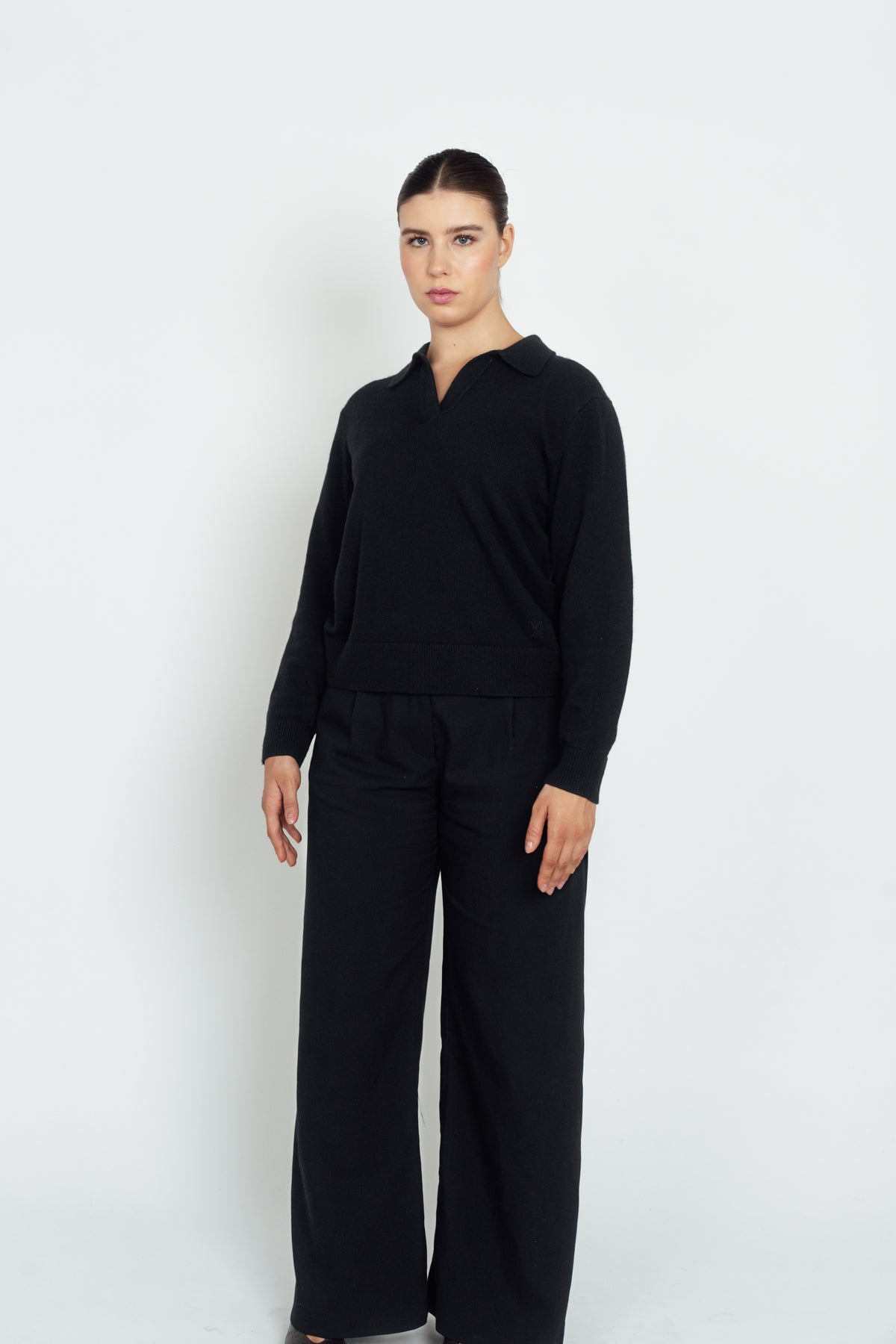 Front view of the black Cashmere-Merino Polo Jumper, showing its open collar and ribbed hem.