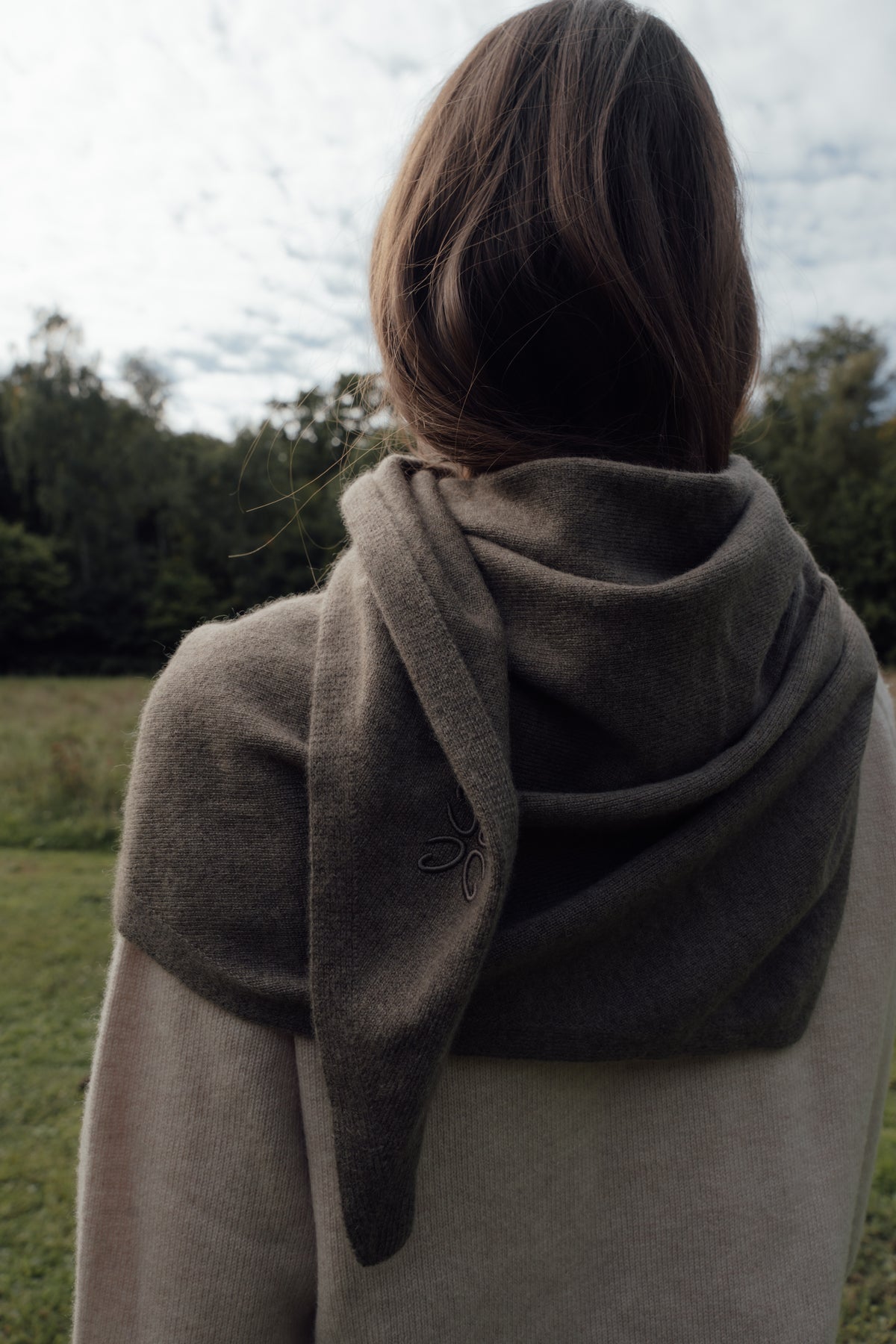 Back view of the dark brown Cashmere Scarf draped around the shoulders, with tonal embroidery on the hanging end.