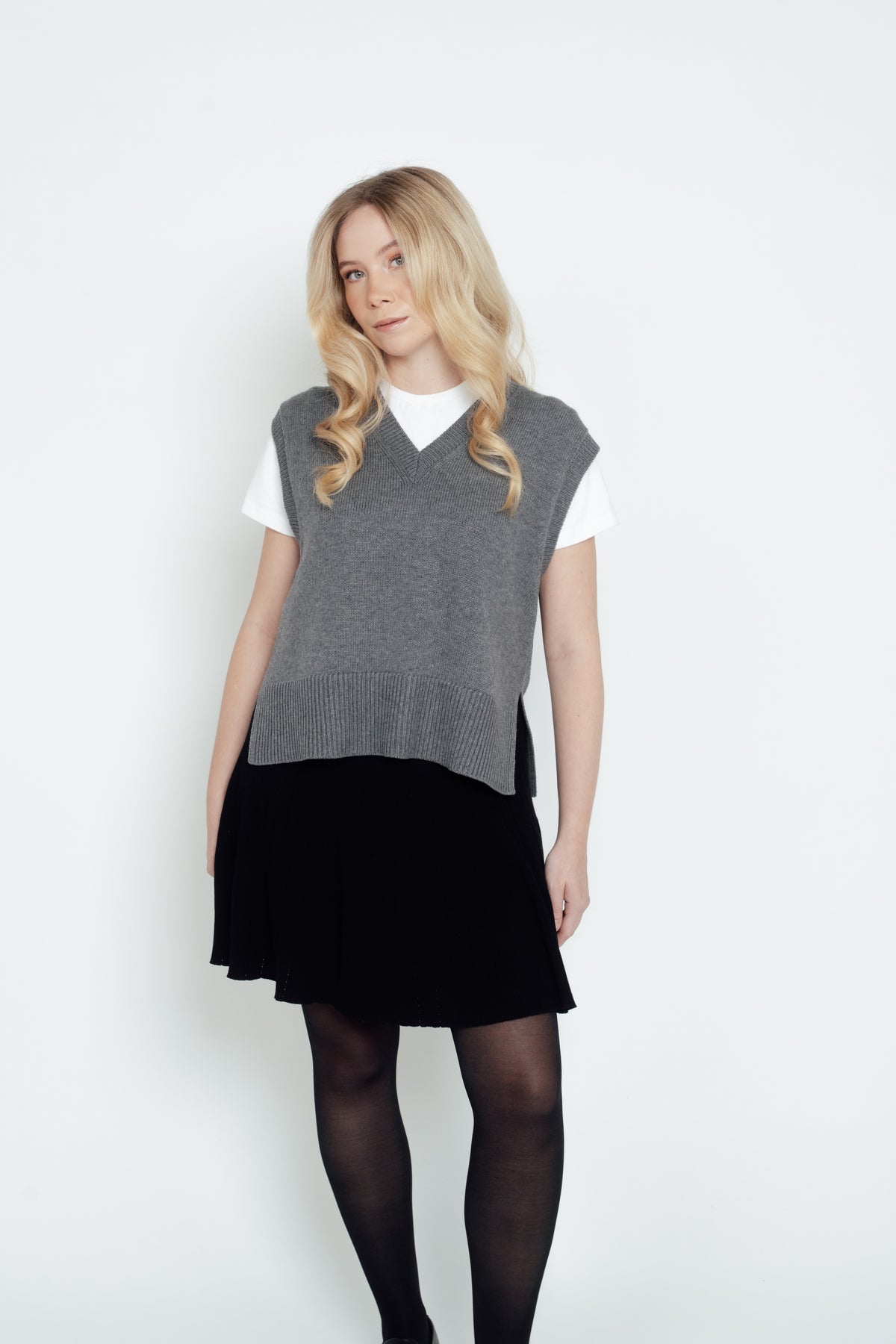 Front view of the grey CYME Merino V-Neck Vest worn over a white T-shirt with a black skirt.