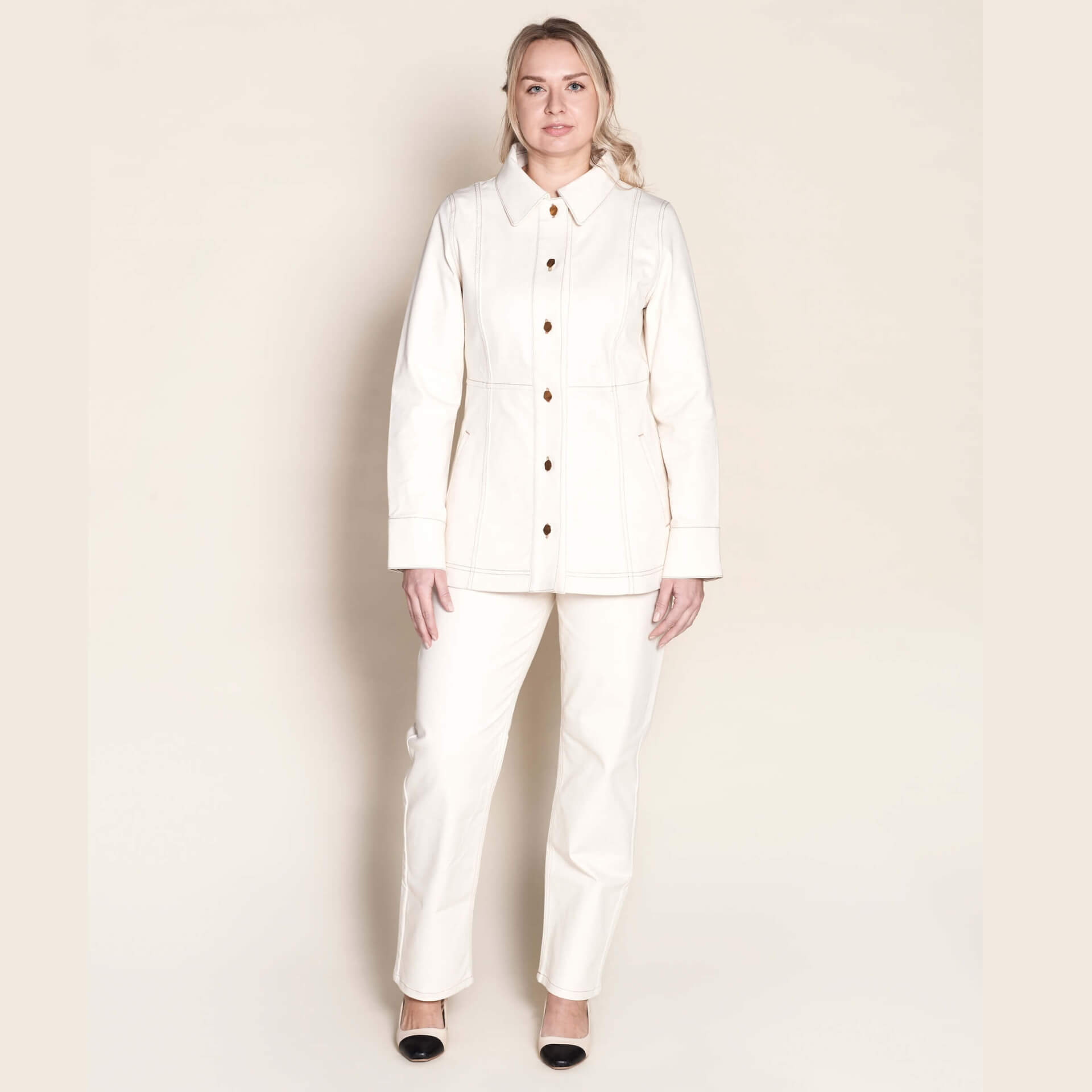 Model stands confidently in Cyme Copenhagen's matching cream denim jacket and trousers set, featuring elegant gold button details, showcasing the timeless appeal and sustainable craftsmanship of Danish design in women's fashion.