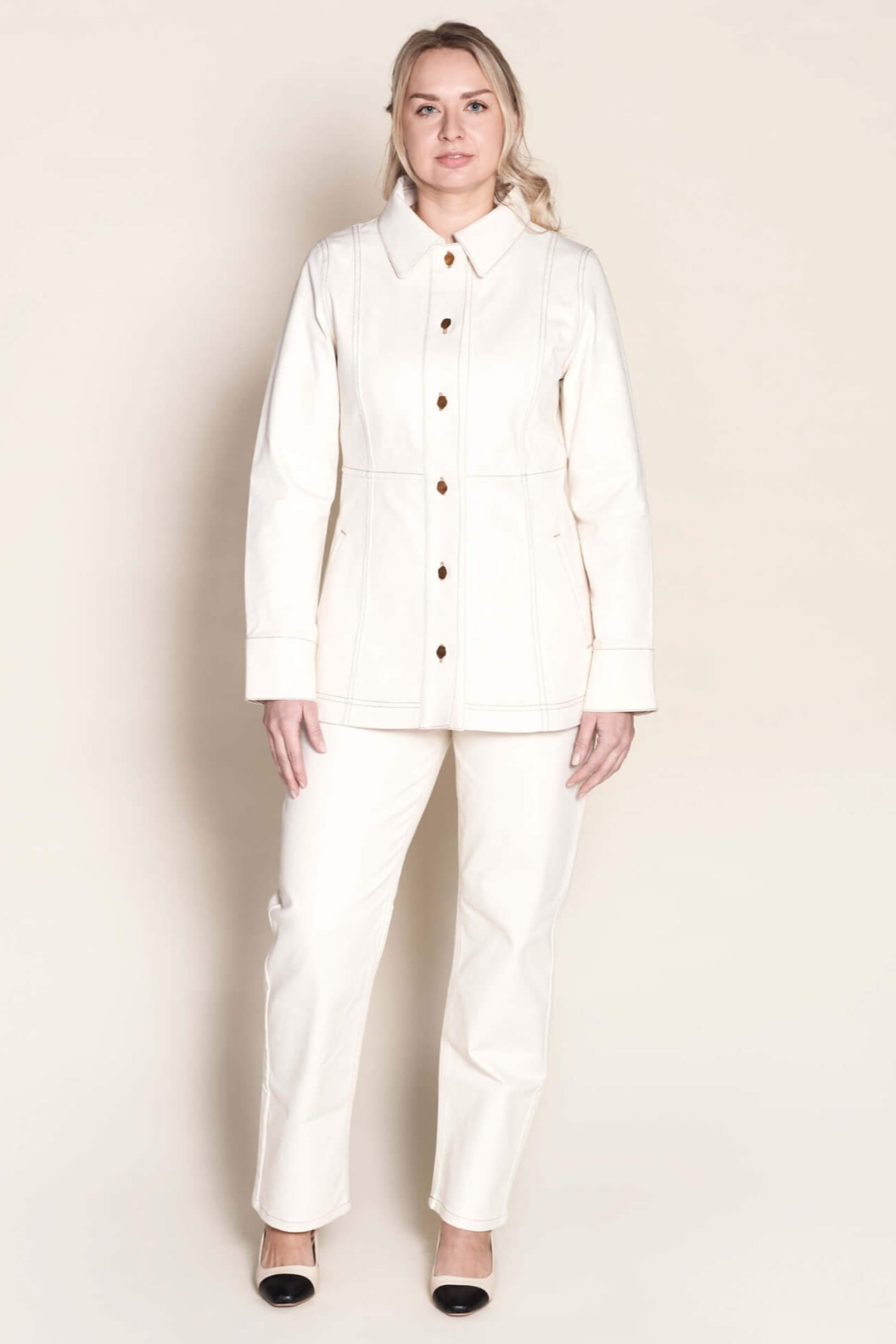 Model stands confidently in Cyme Copenhagen's matching cream denim jacket and trousers set, featuring elegant gold button details, showcasing the timeless appeal and sustainable craftsmanship of Danish design in women's fashion.