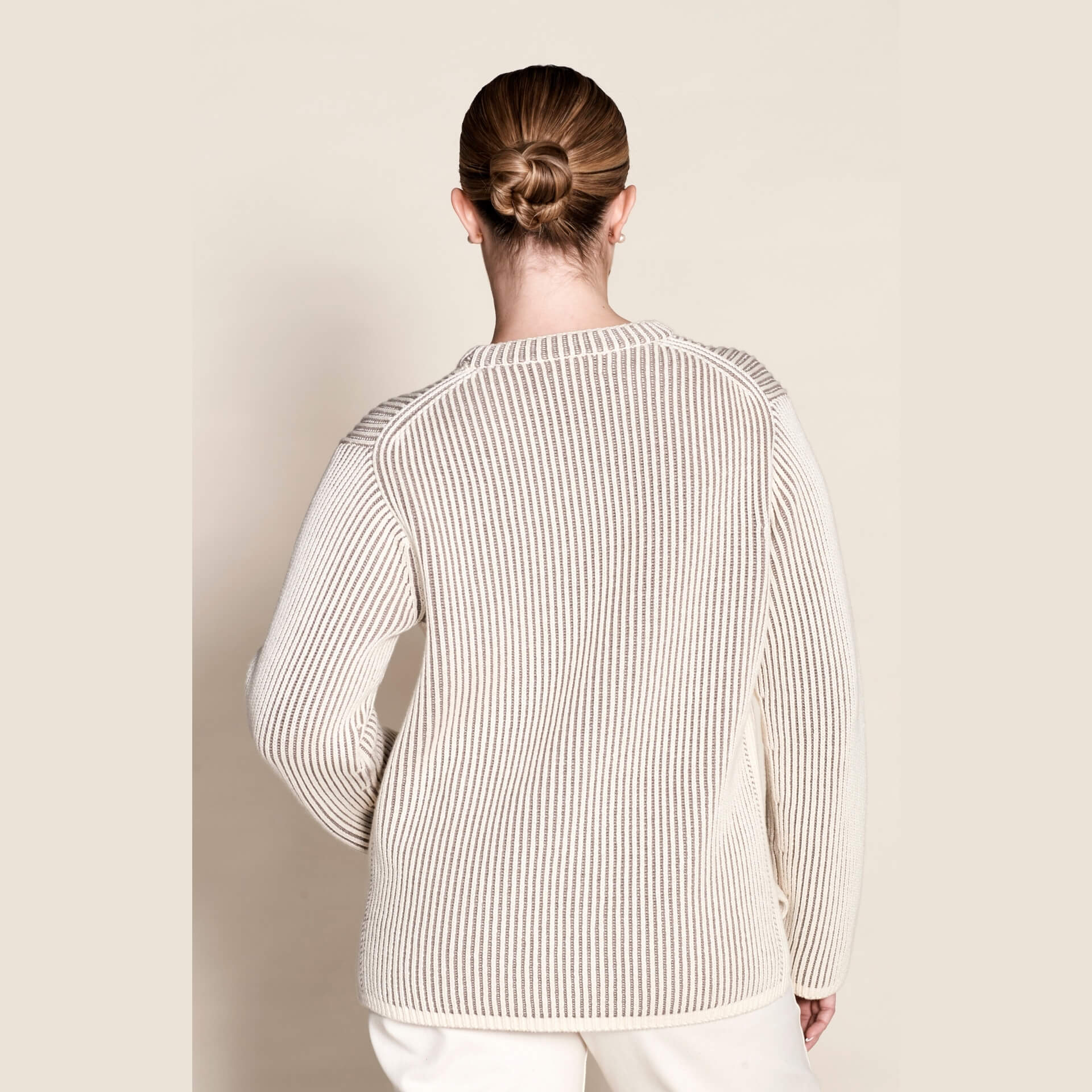 Rear view of a ribbed cashmere knit sweater in cream by Cyme Copenhagen, detailing the fine craftsmanship and use of natural materials that define the brand's sustainable and timeless Scandinavian fashion.