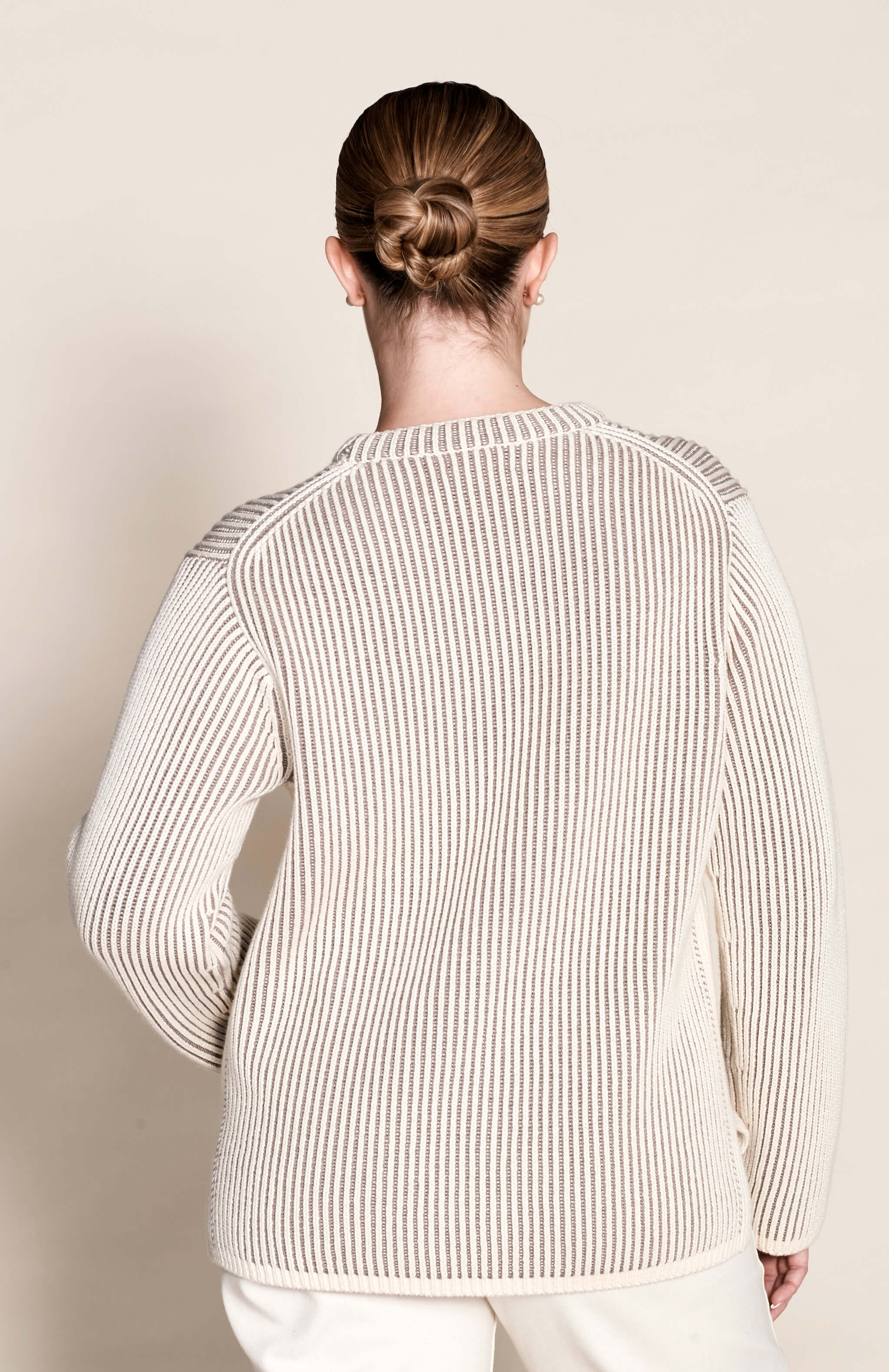 Rear view of a ribbed cashmere knit sweater in cream by Cyme Copenhagen, detailing the fine craftsmanship and use of natural materials that define the brand's sustainable and timeless Scandinavian fashion.