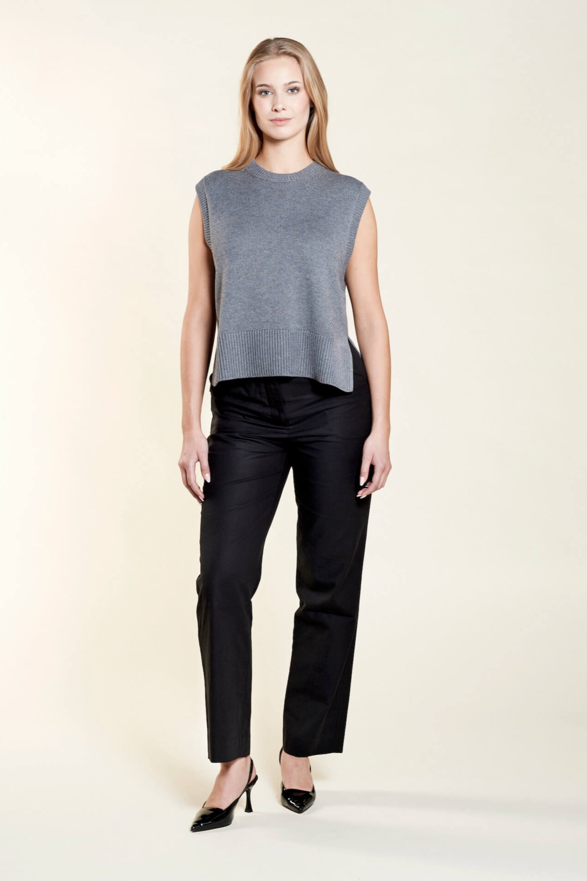 A model confidently wears a Cyme Copenhagen classic black trousers with a chic black cropped top composed with lyocell, highlighting the brand's flair for combining sustainable fashion with timeless Scandinavian design.