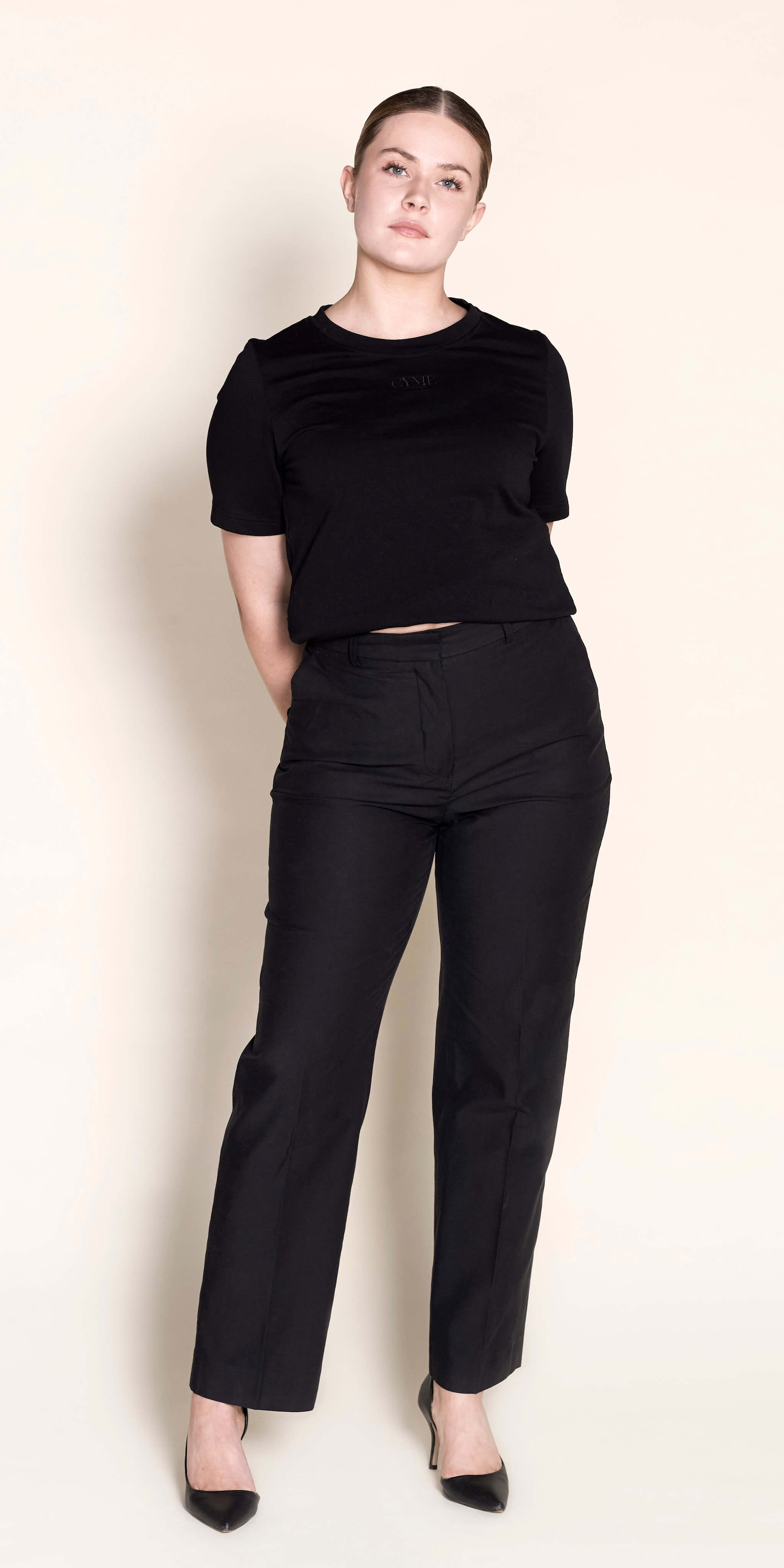 A model confidently wears a Cyme Copenhagen classic black trousers with a chic black cropped top composed with lyocell, highlighting the brand's flair for combining sustainable fashion with timeless Scandinavian design.
