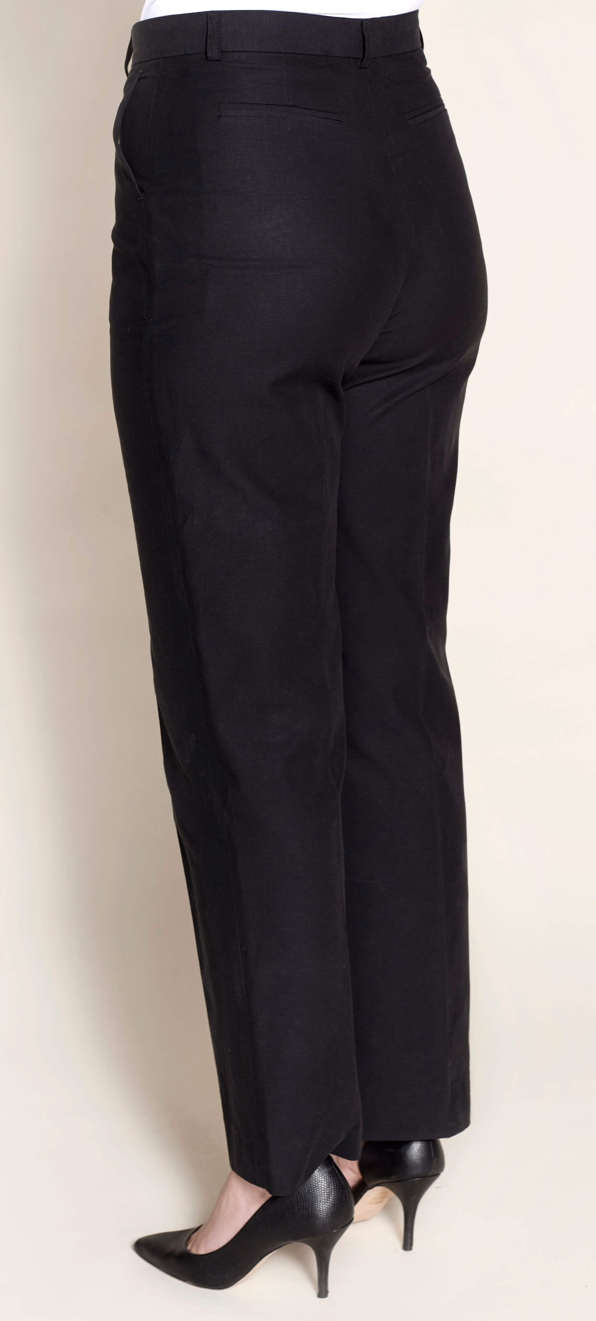 Side view of a model in Cyme Copenhagen's tailored black lyocell trousers available in plus-size, highlighting a nice fit with a sleek design, embodying the essence of sustainable and timeless Scandinavian fashion.