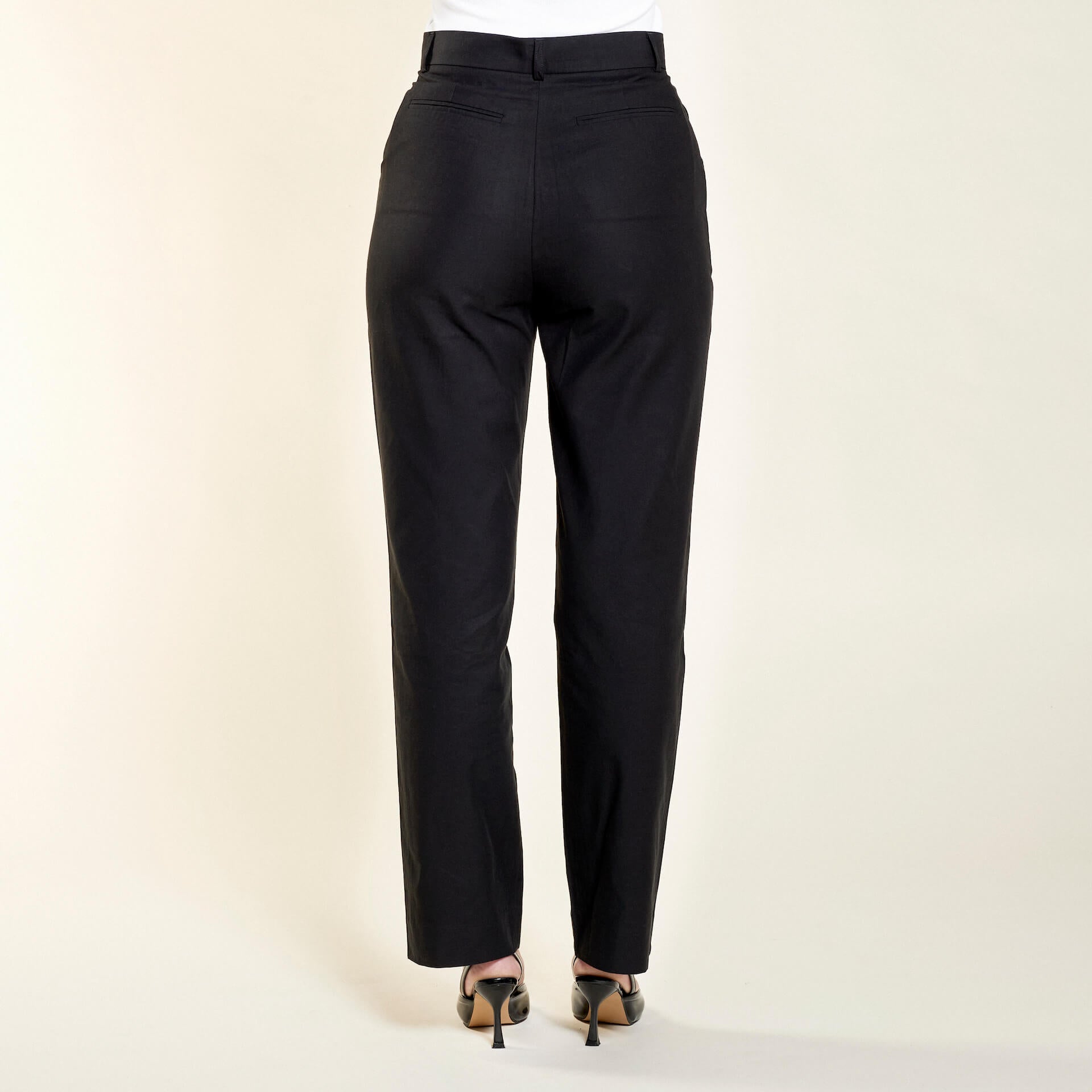 Side view of a model in Cyme Copenhagen's tailored black lyocell trousers available in plus-size, highlighting a nice fit with a sleek design, embodying the essence of sustainable and timeless Scandinavian fashion.