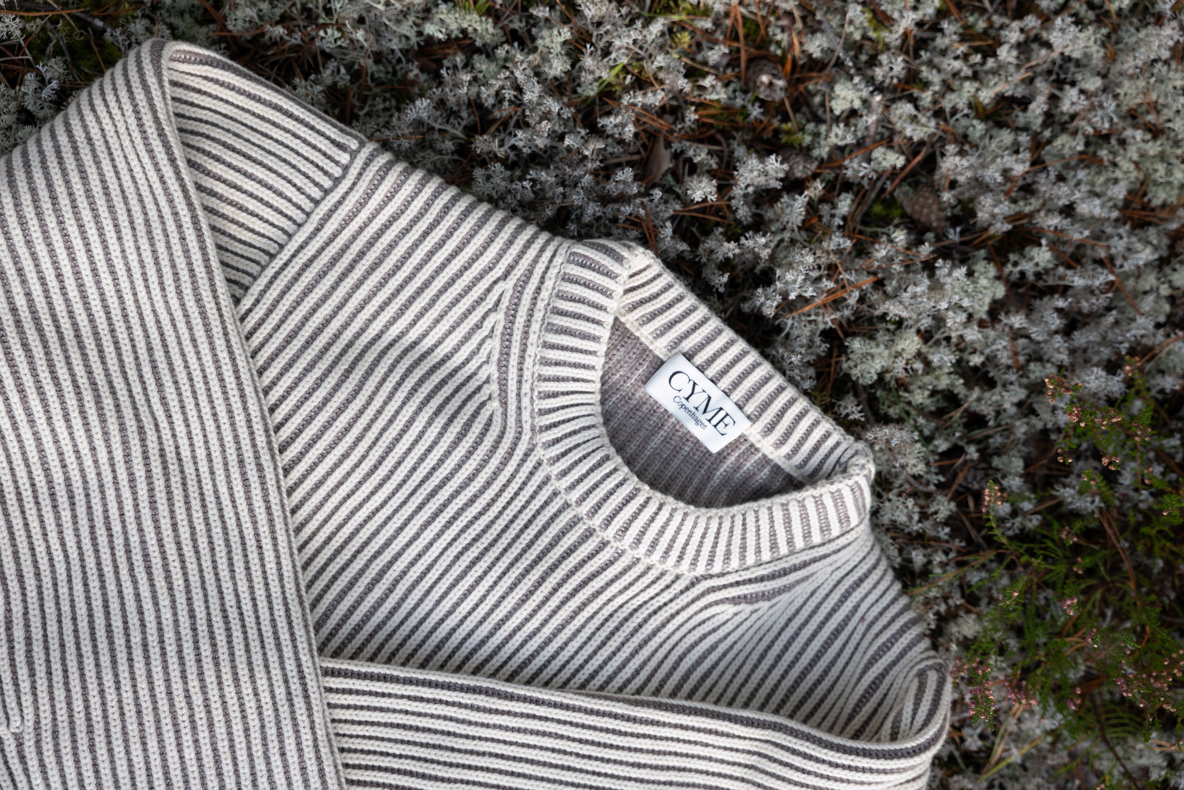 Striped sweater with a brand label against a natural background