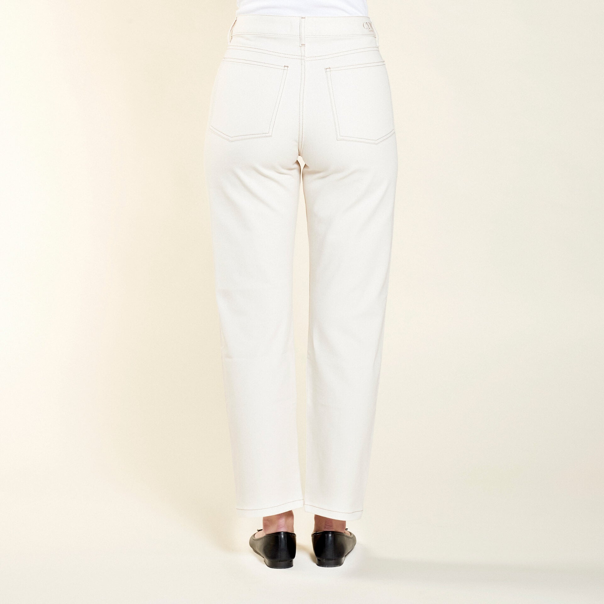 Rear view of Cyme Copenhagen's cream denim trousers, featuring a clean and classic design with signature branding on the waistband, showcasing the sustainable and chic Danish fashion ethos.