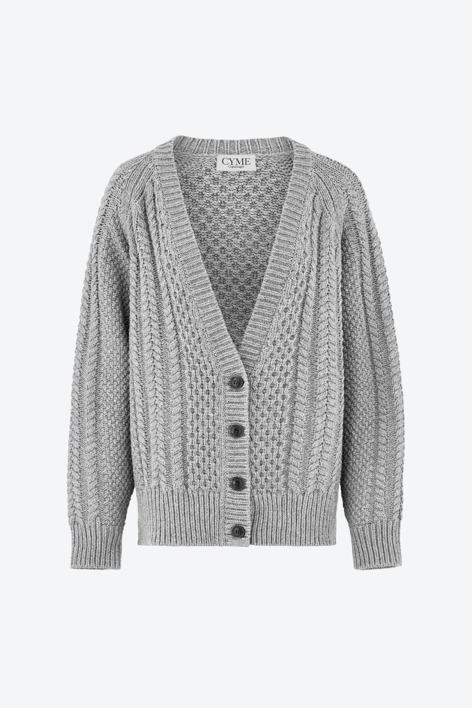 Front view of a light grey cable-knit cardigan with a deep V-neckline and button-up closure, featuring a textured knit pattern and ribbed cuffs and hem, displayed on a plain background.