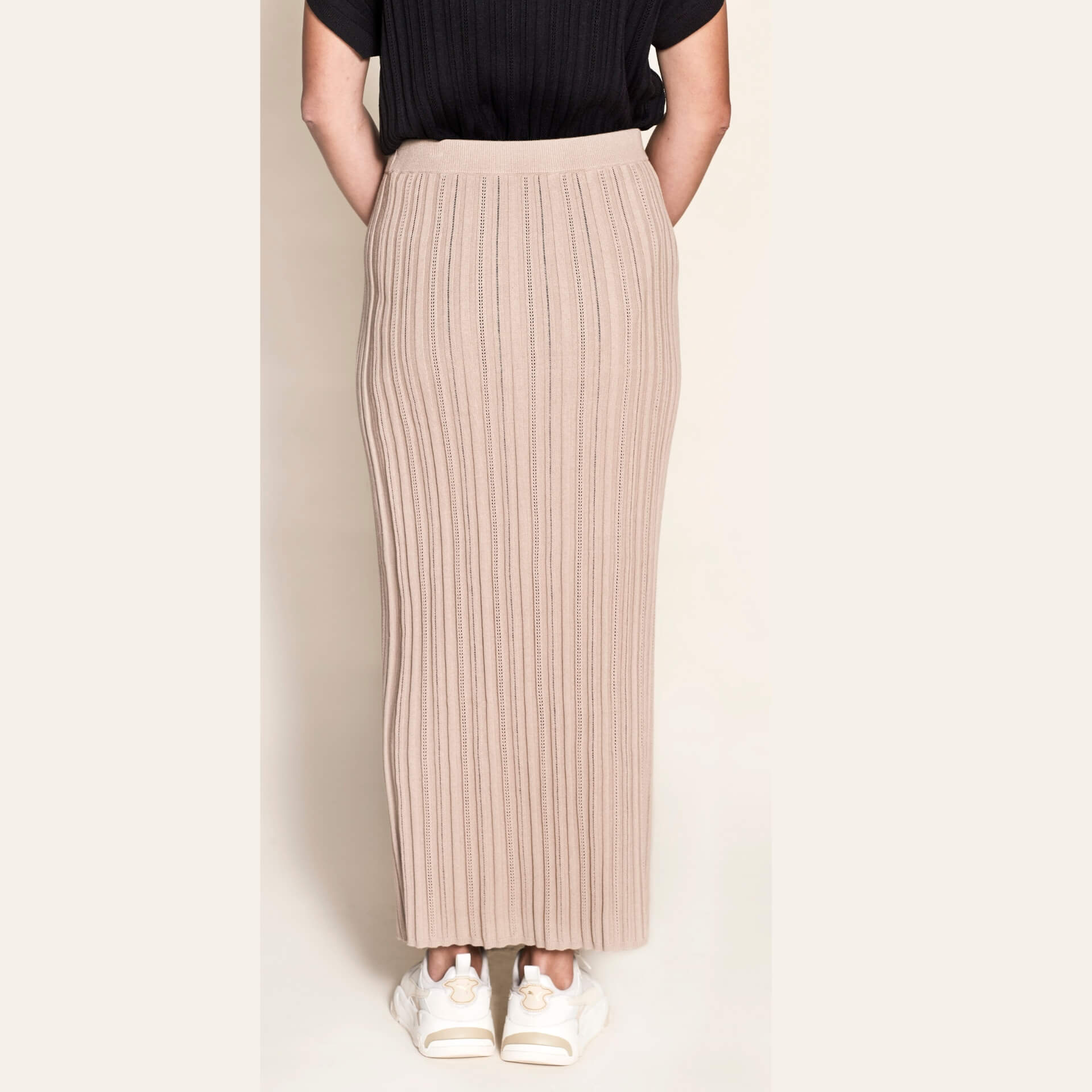 Rear view of a Cyme Copenhagen pointelle ribbed knit pencil skirt in a natural beige tone, showcasing the elegance and sustainable quality of Scandinavian womenswear.