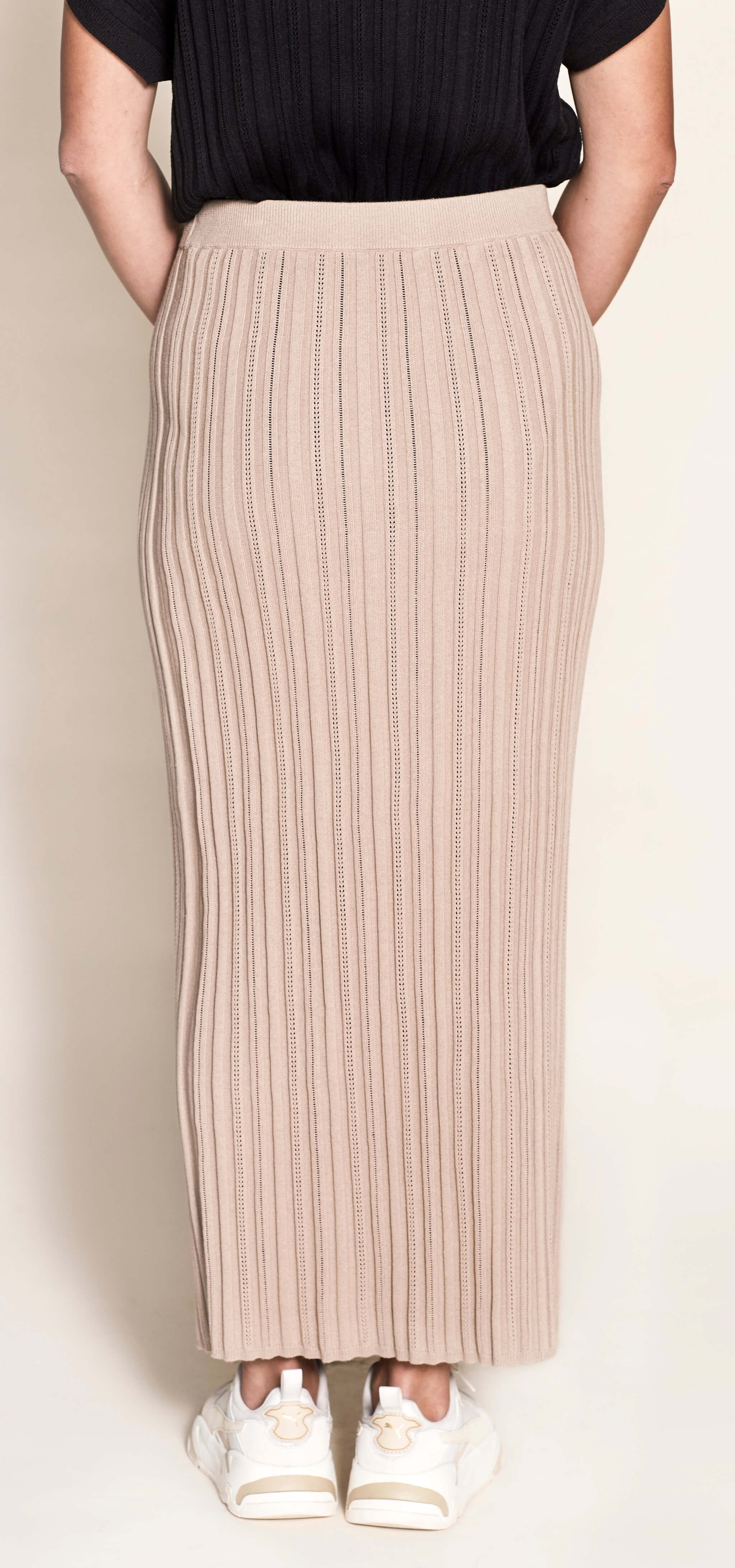 Rear view of a Cyme Copenhagen pointelle ribbed knit pencil skirt in a natural beige tone, showcasing the elegance and sustainable quality of Scandinavian womenswear.