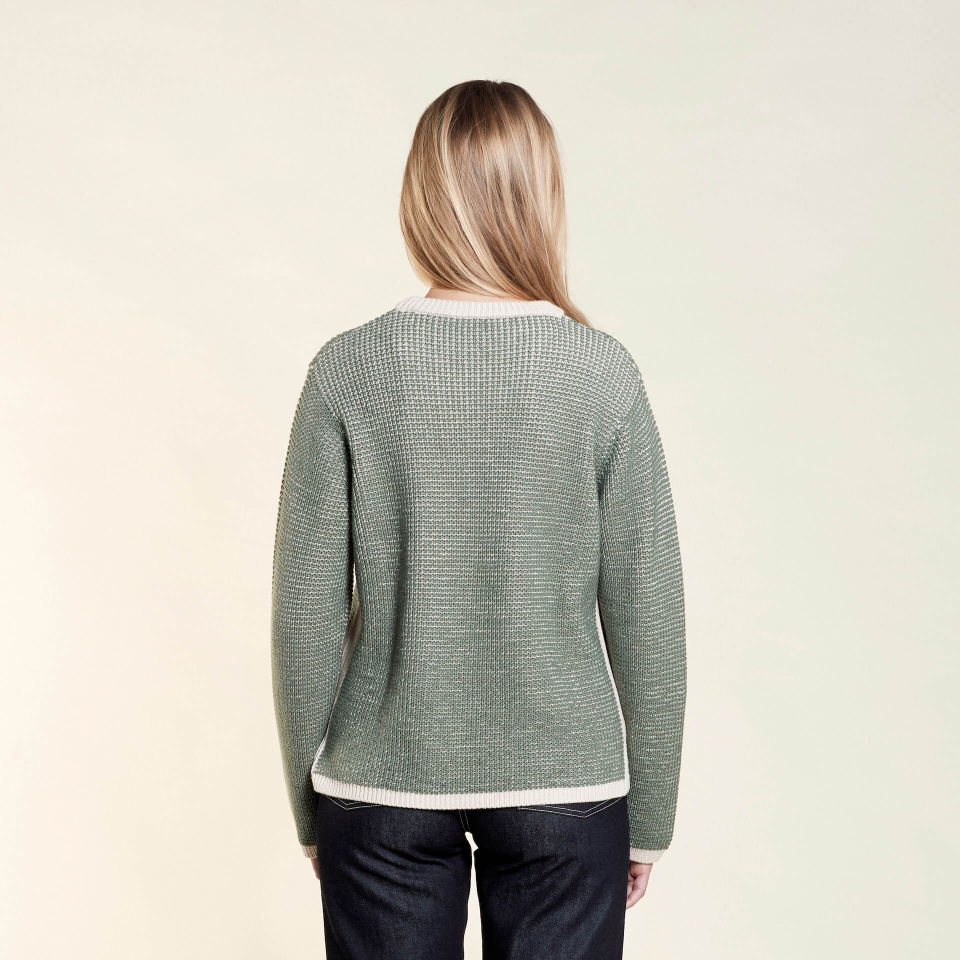 Back view of a model wearing a green textured knit sweater from CYME Copenhagen, highlighting the sweater's fit and texture. The sweater features a slightly loose fit with contrasting light-colored trim at the hem and cuffs.