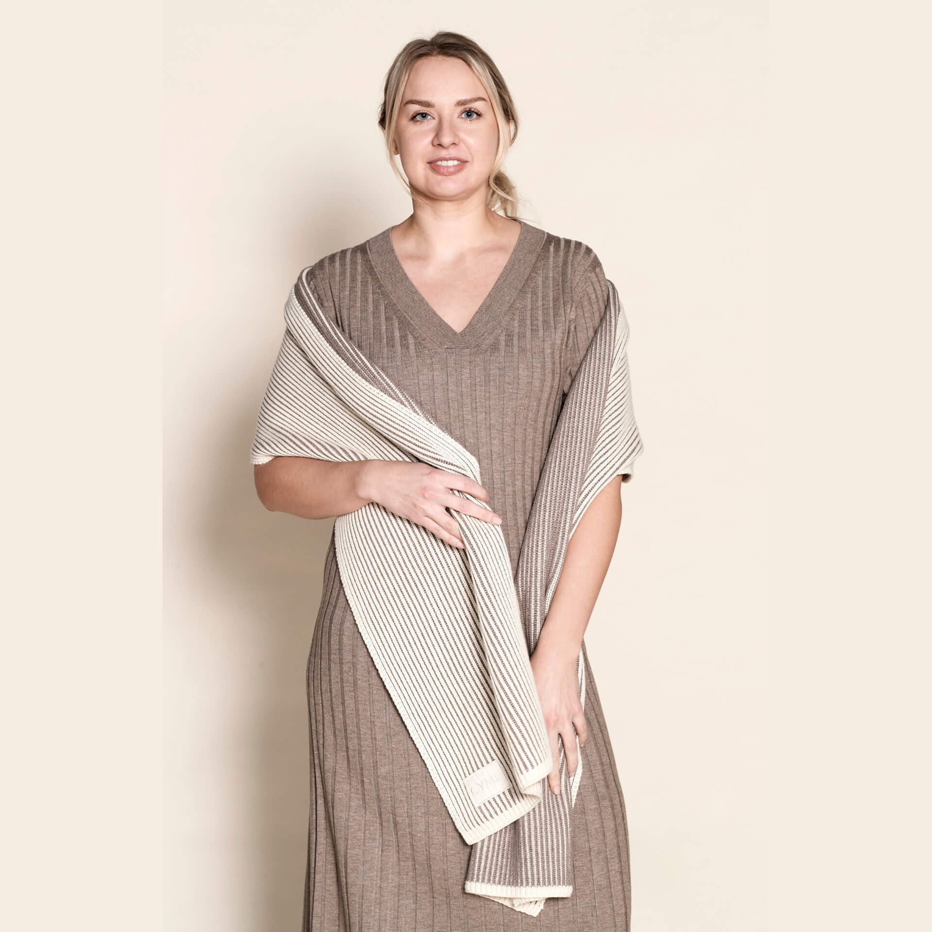 Model draped in a Cyme Copenhagen luxurious cashmere knit dress paired with a contrasting striped scarf, showcasing the fusion of natural materials and timeless fashion in Danish design.