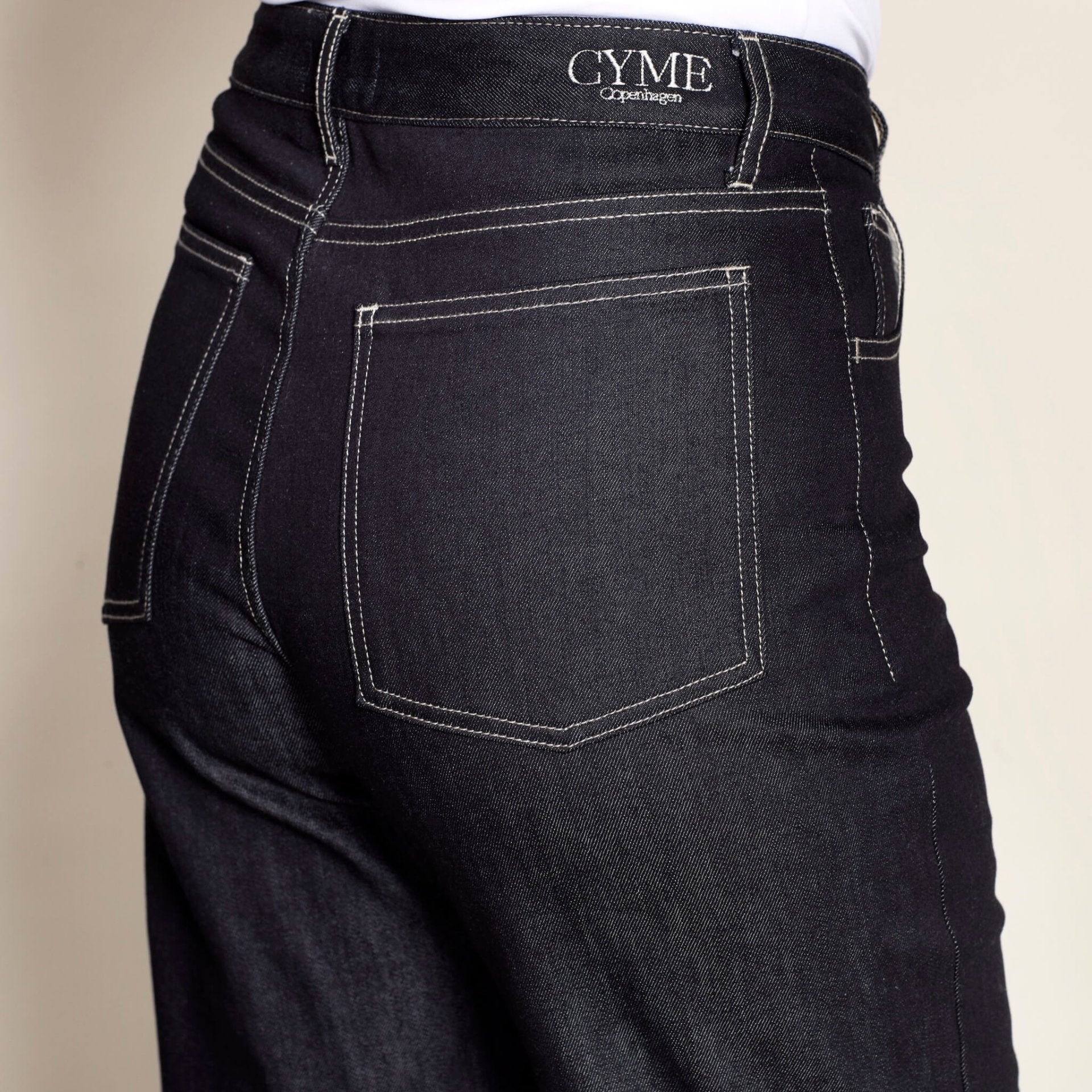 Detail of Cyme Copenhagen's premium denim jeans featuring contrast stitching and the brand's logo, exemplifying the luxury and craftsmanship of Danish designer clothing.