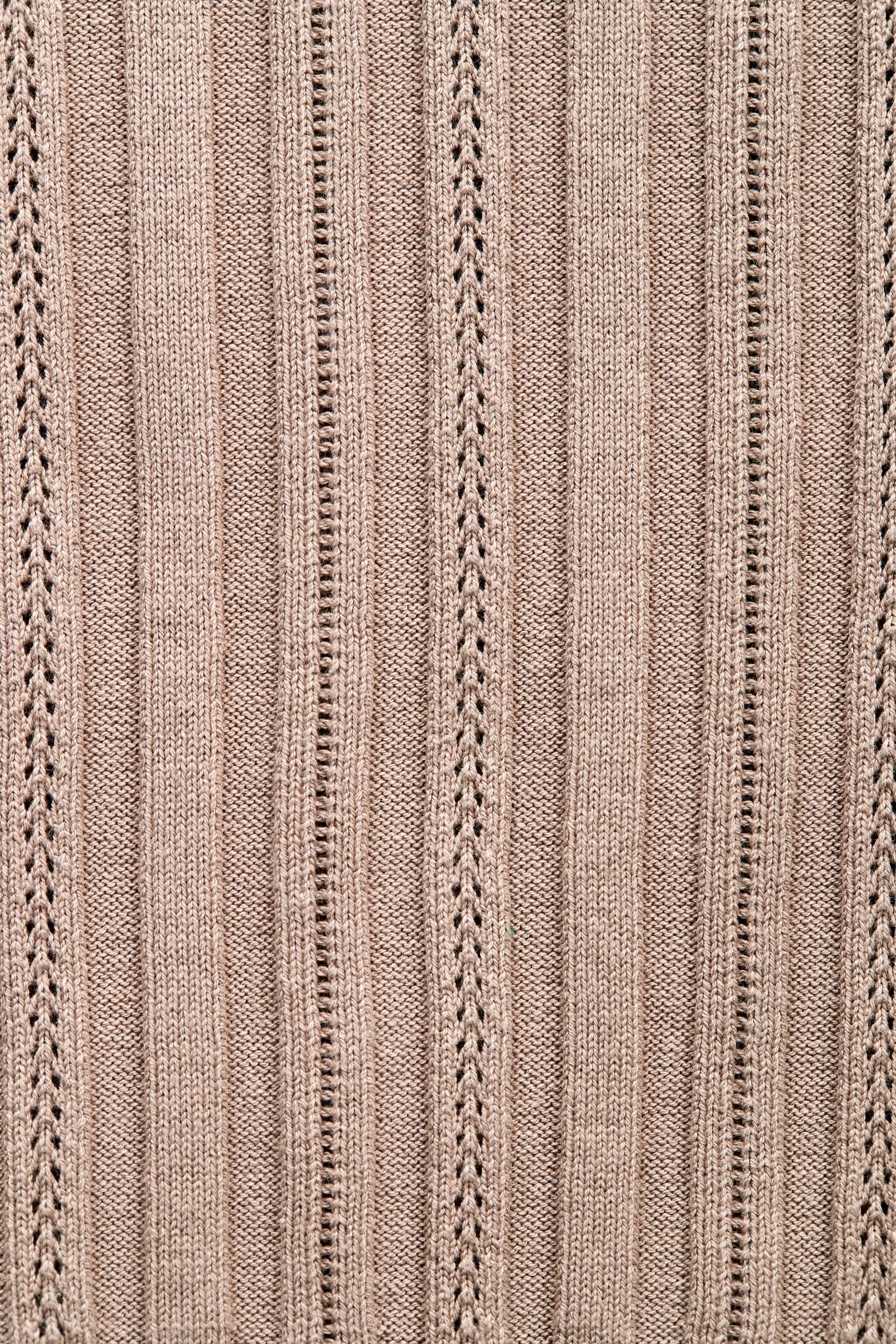 Close-up of the intricate knit pattern on a taupe garment, showcasing Cyme Copenhagen's attention to detail and craftsmanship in sustainable materials for their Danish fashion brand, specializing in women's clothing.