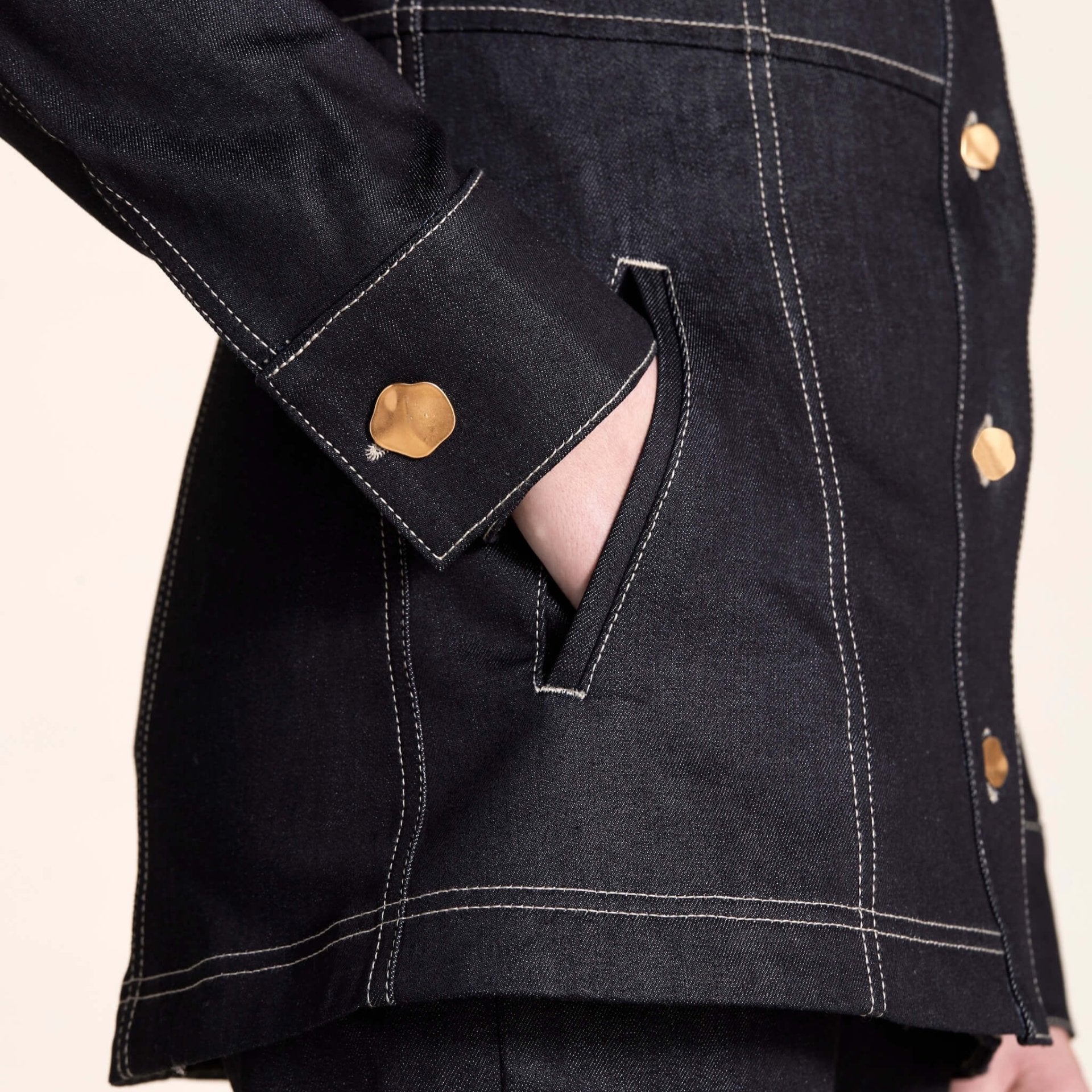 Close-up on the detail of a Cyme Copenhagen denim jacket with golden button cuff, showcasing the brand's attention to detail and dedication to ethical fashion with a Scandinavian touch.