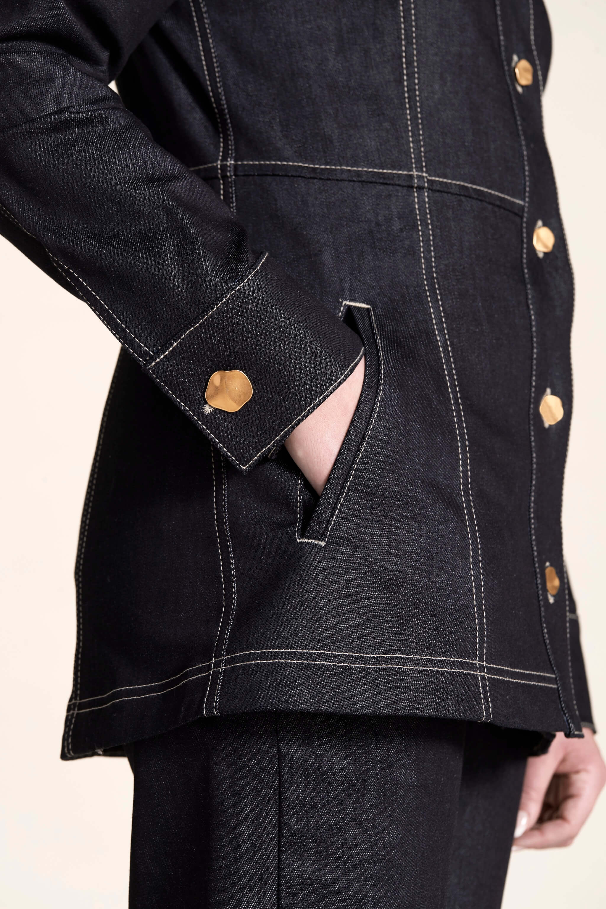 Close-up on the detail of a Cyme Copenhagen denim jacket with golden button cuff, showcasing the brand's attention to detail and dedication to ethical fashion with a Scandinavian touch.