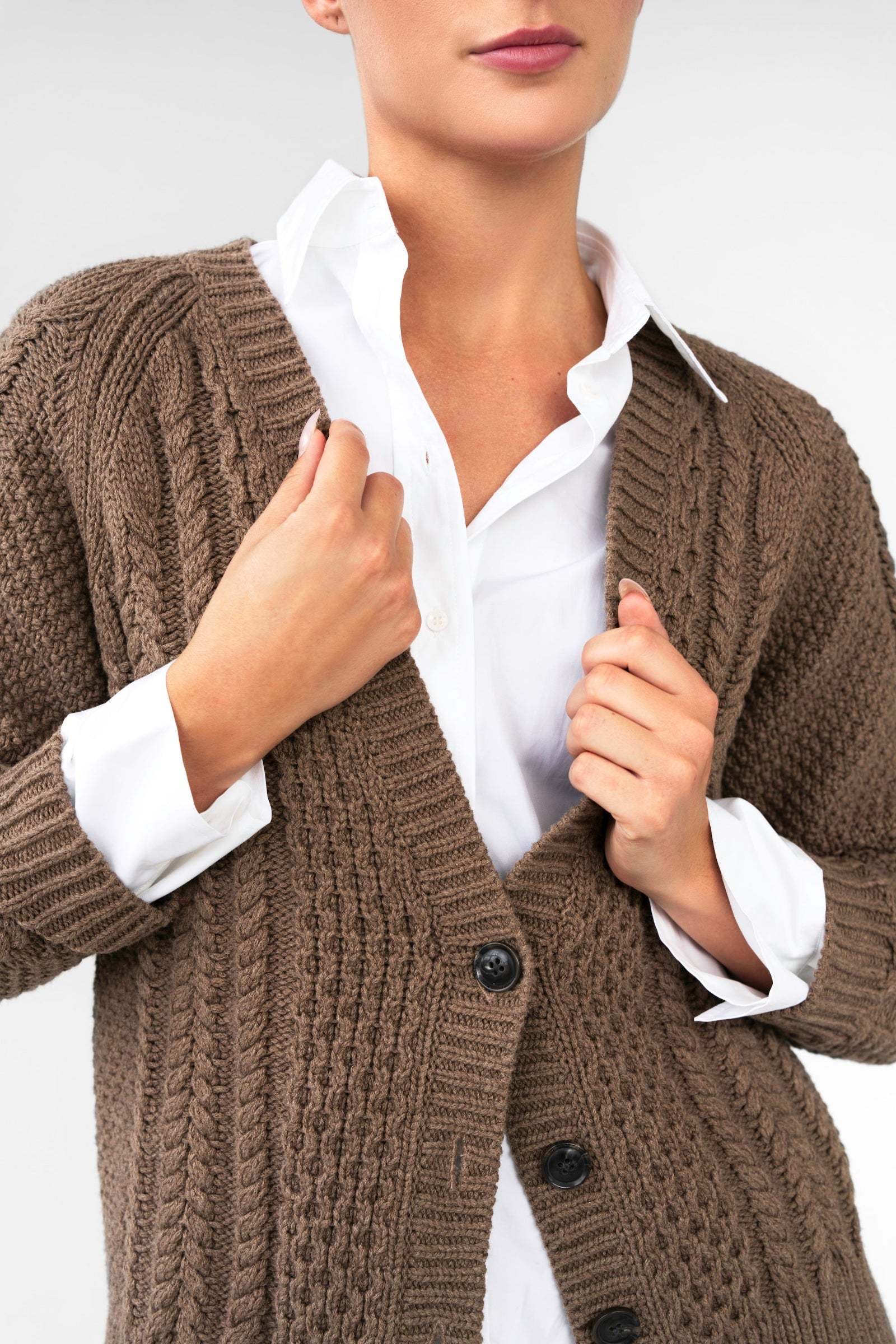 Brown knitted cardigan over a white shirt on a plain background