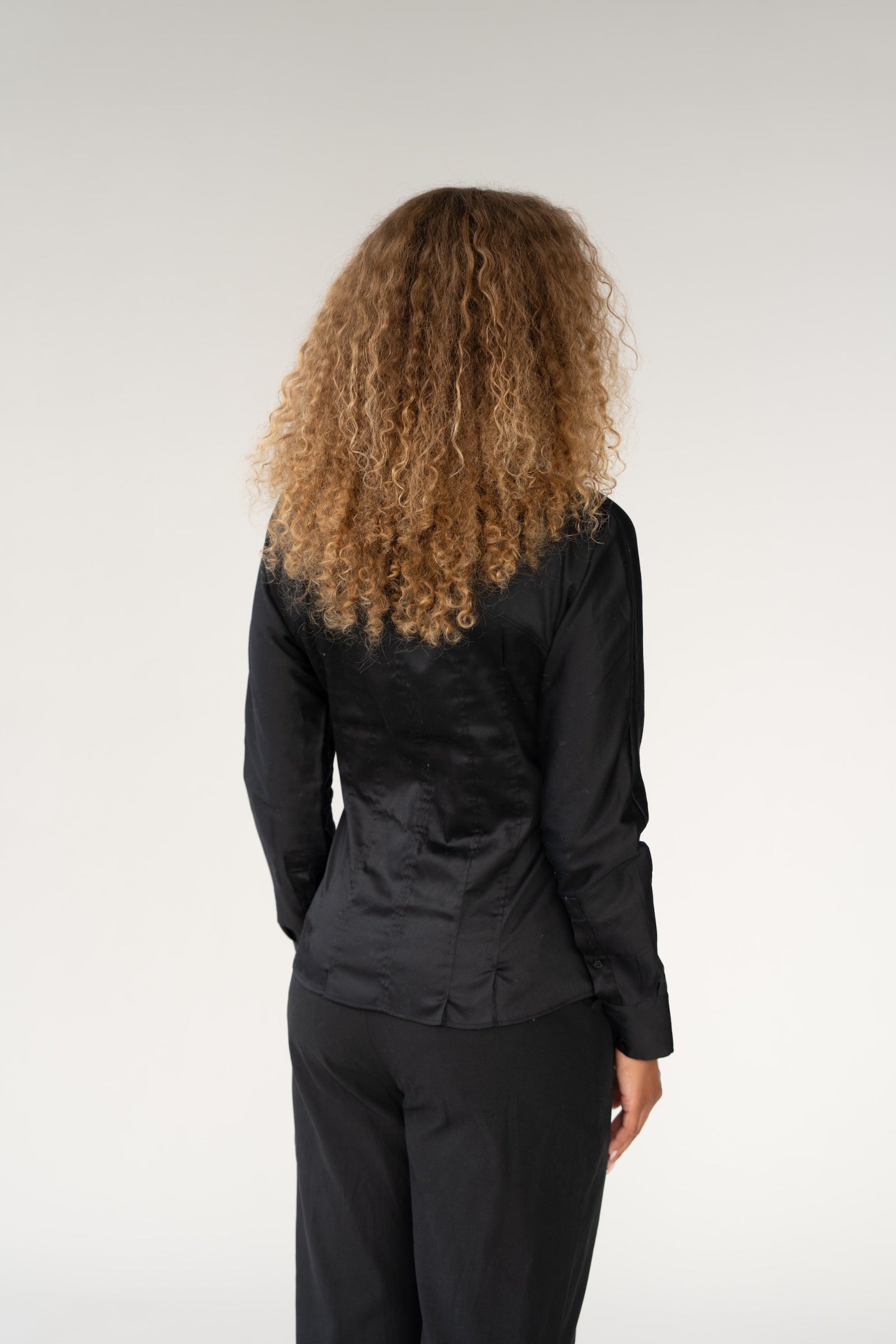 Person wearing a black outfit with a plain background