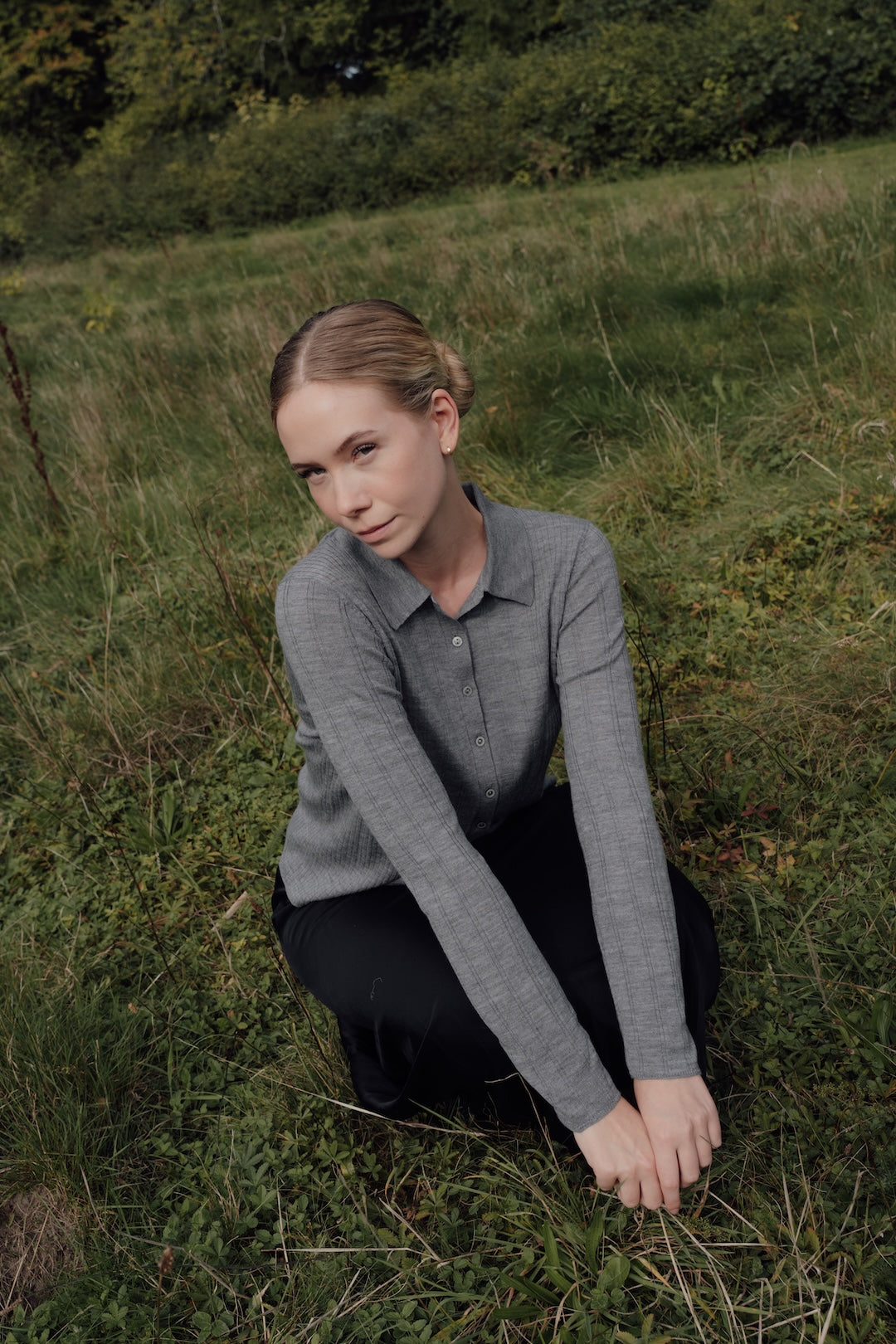 Grey Merino Polo Cardigan shown on a seated model, with its collar and long sleeves visible.