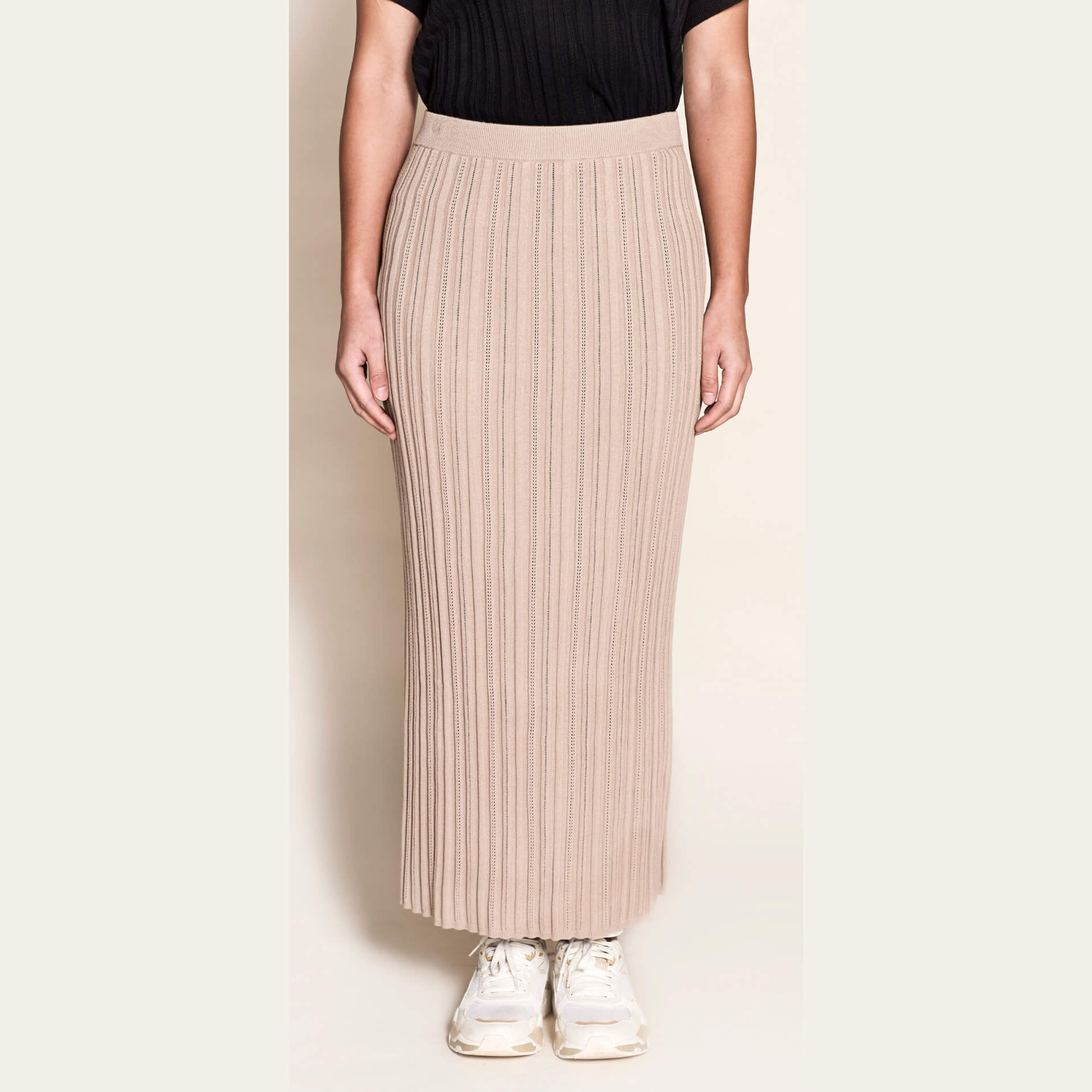 Front view of a timeless ribbed knit pencil skirt by Cyme Copenhagen, paired with a black top and white sneakers, showcasing versatile and sustainable Scandinavian design.