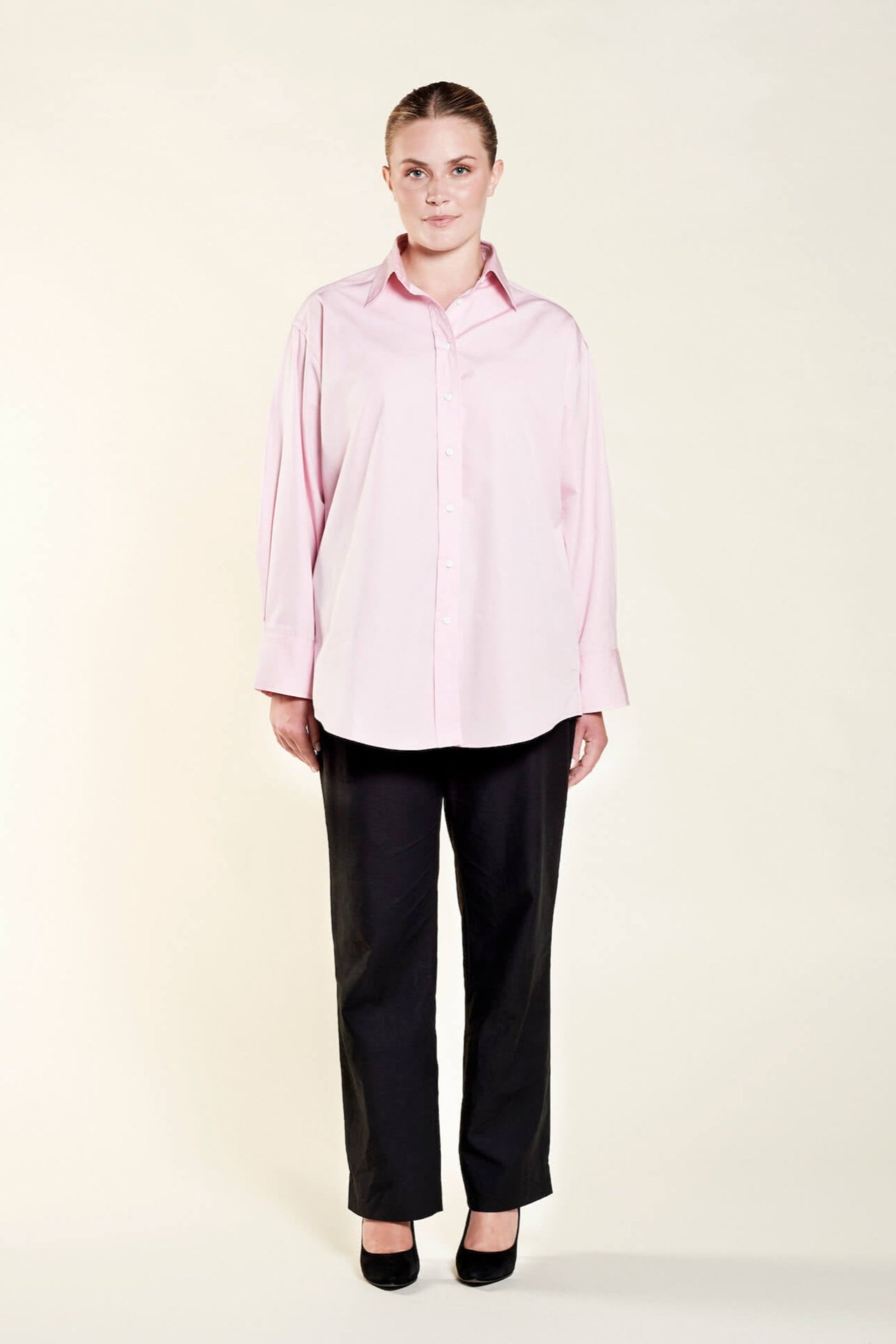 Model presenting Cyme Copenhagen's elegant oversized pink shirt, featuring a relaxed cut that combines comfort with Danish design, reflecting the brand's dedication to sustainable fashion and offering chic women's clothing for all sizes.
