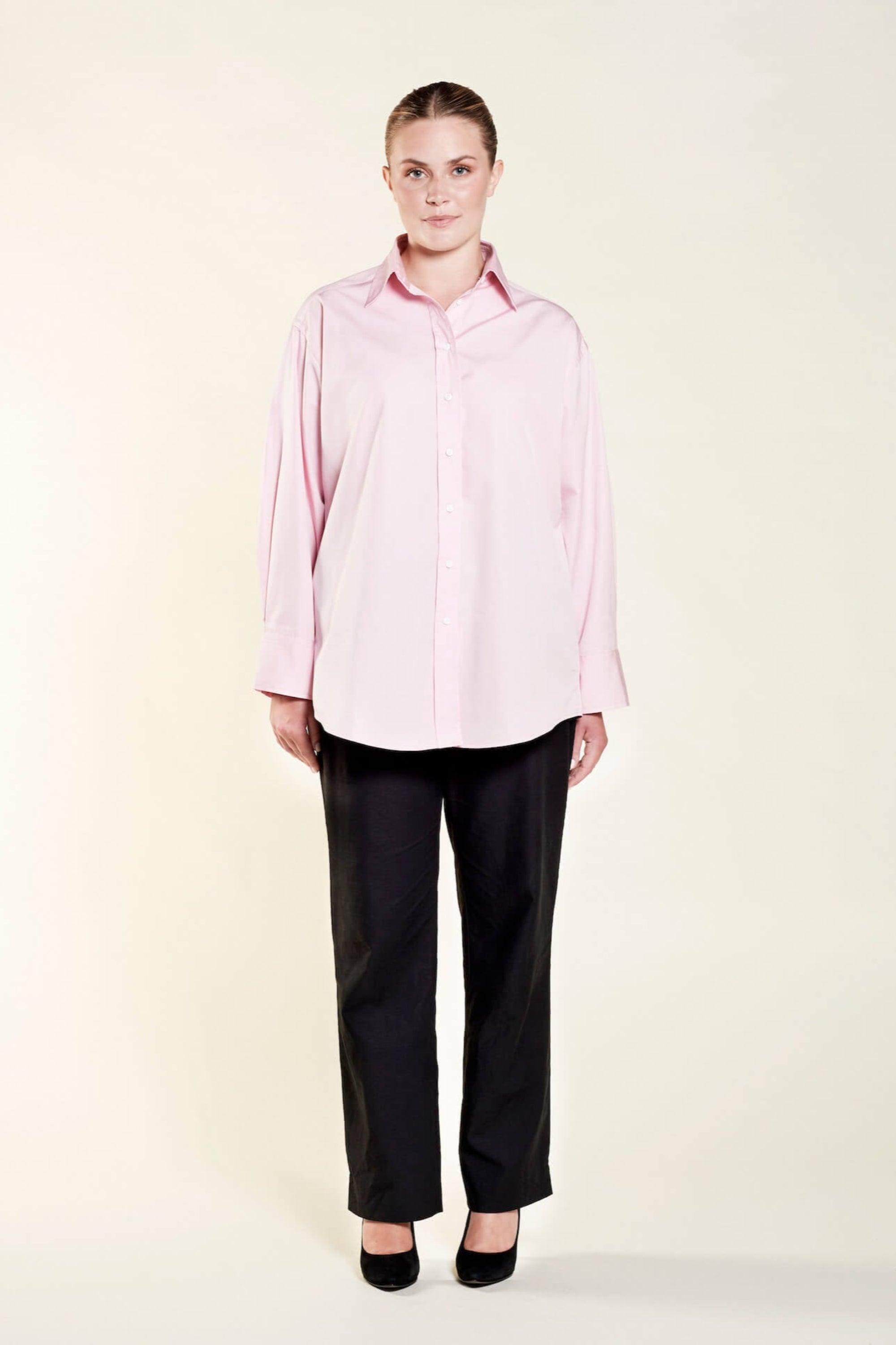 Model presenting Cyme Copenhagen's elegant oversized pink shirt, featuring a relaxed cut that combines comfort with Danish design, reflecting the brand's dedication to sustainable fashion and offering chic women's clothing for all sizes.