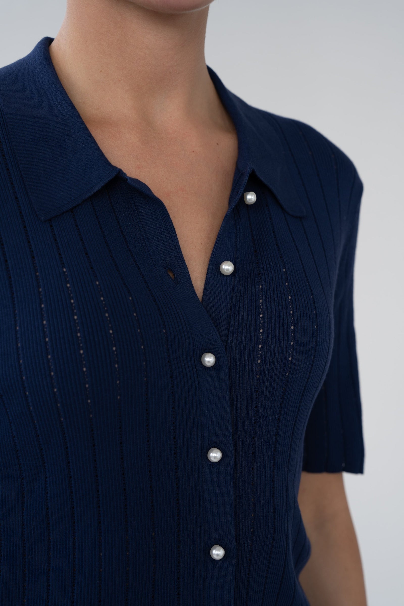 Navy blue dress with white buttons on a plain background