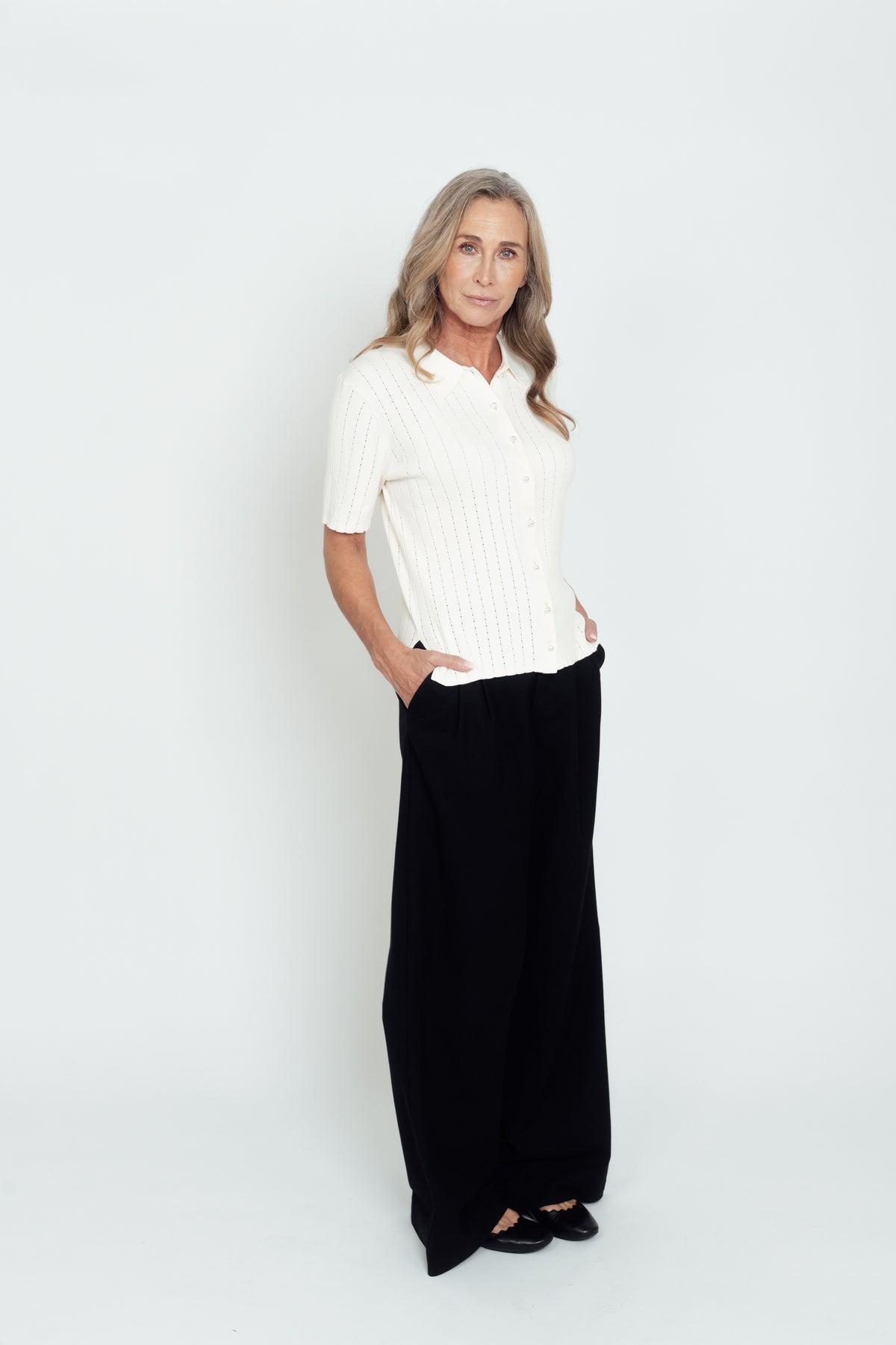 Ivory Pointelle Polo Shirt worn with black trousers, shown at a slight angle.