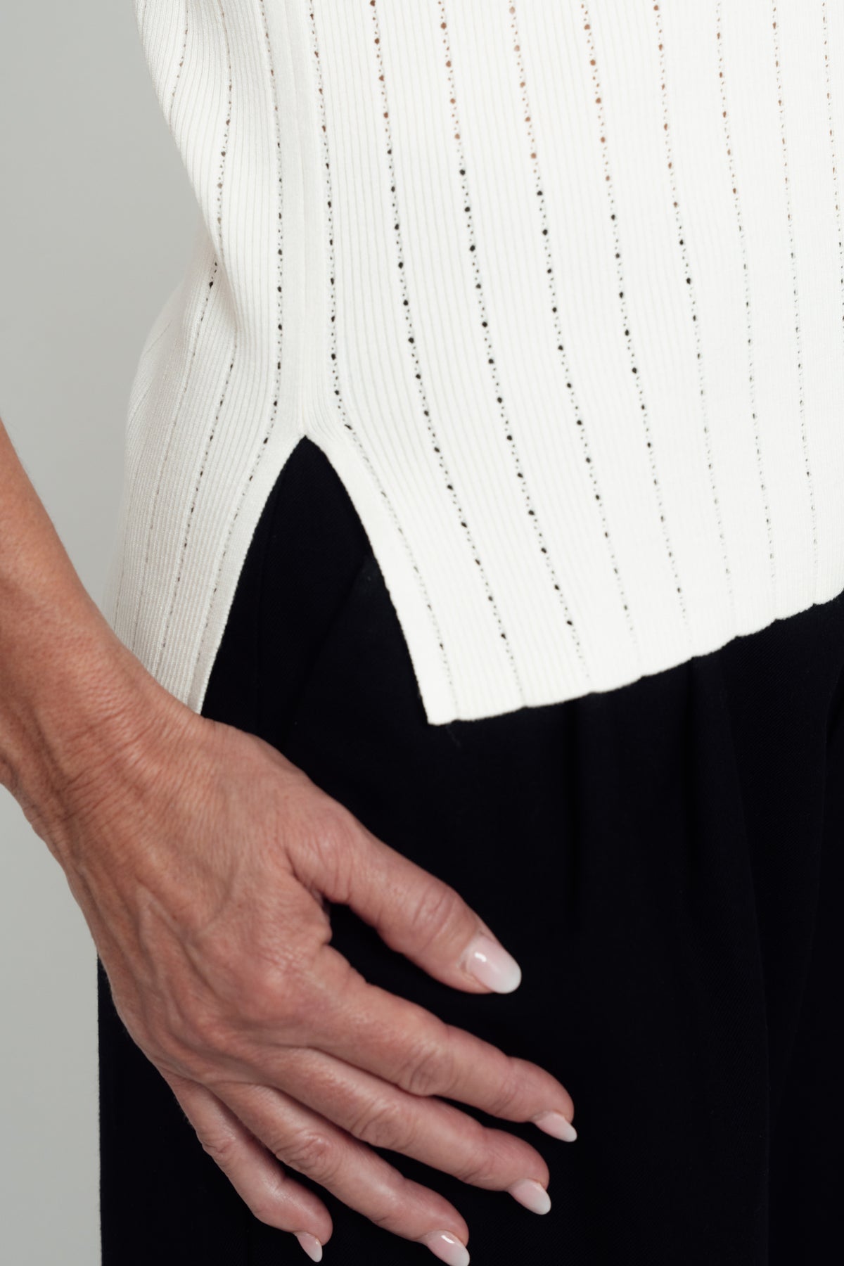 Close-up of the ivory Pointelle Polo Shirt's side slit and pointelle knit.