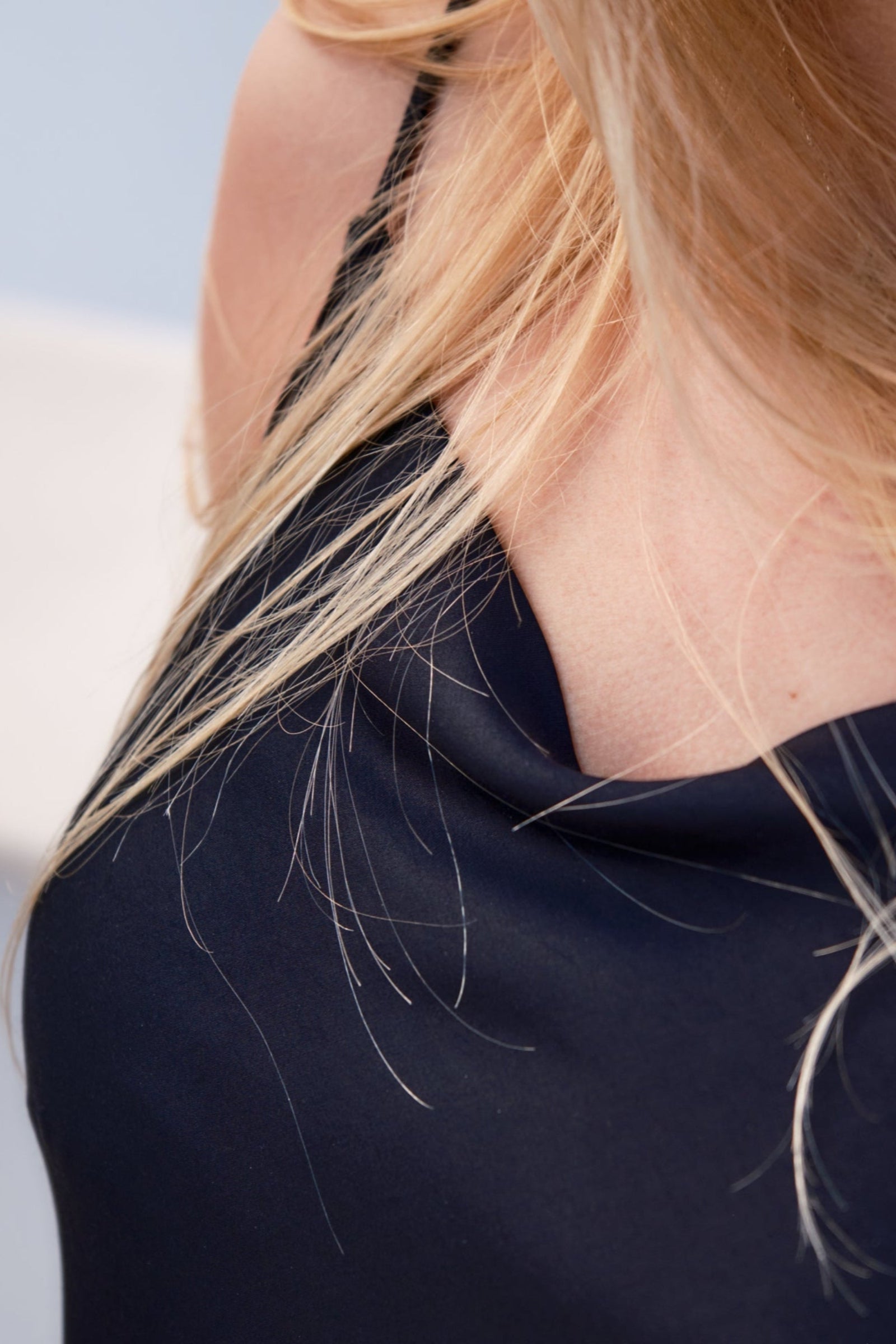 Close-up of a person wearing a black top with blonde hair.