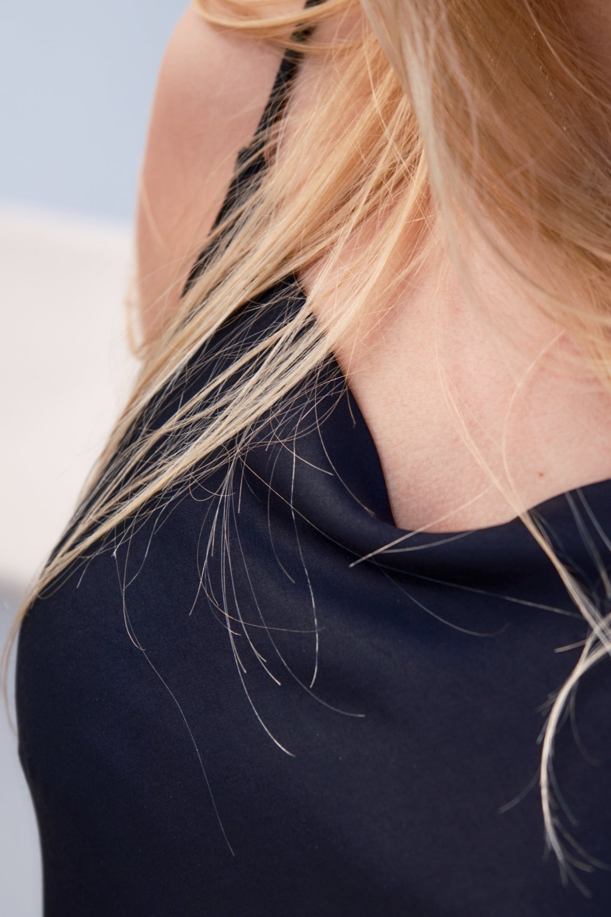 Close-up of a person wearing a black top with blonde hair.