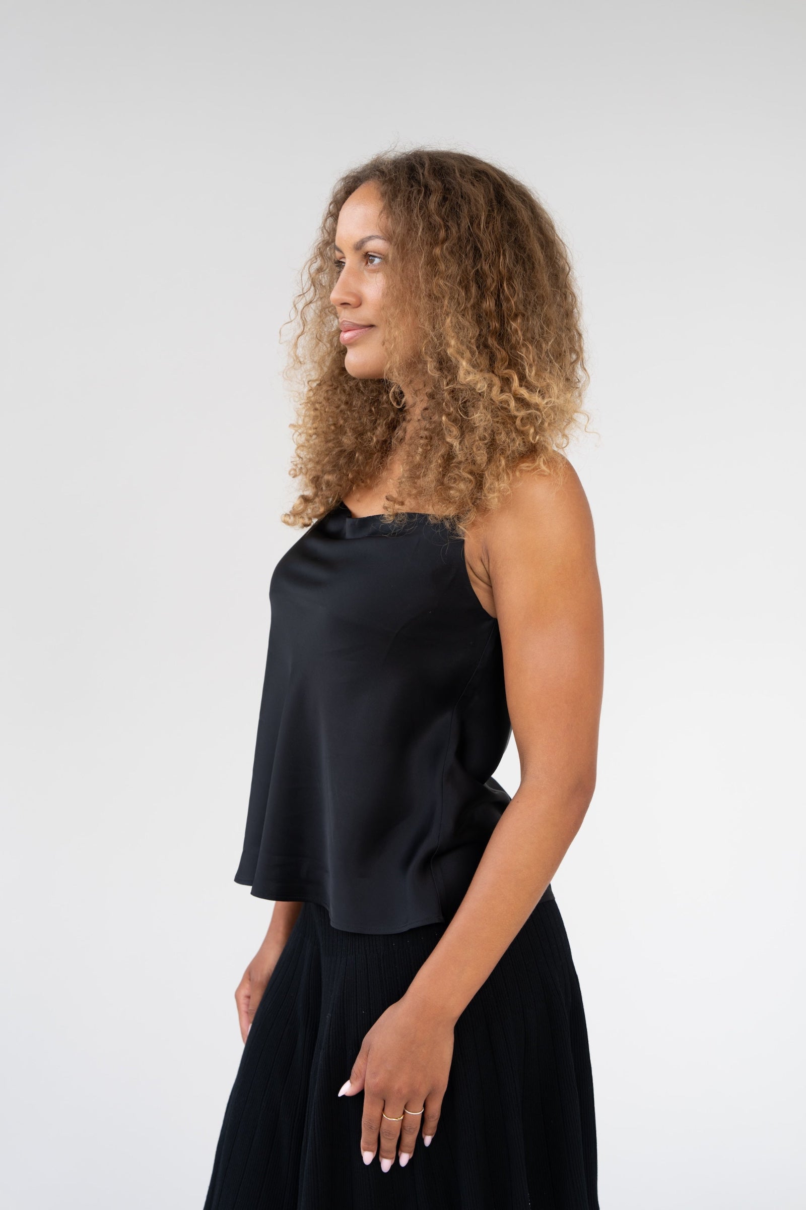 Woman wearing a black sleeveless top and black skirt against a white background