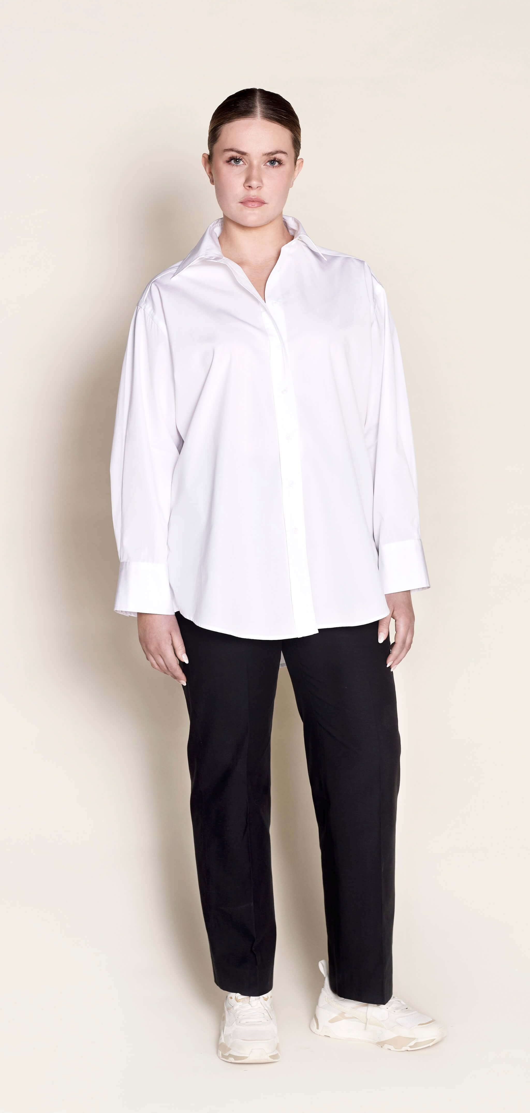 Model in a Cyme Copenhagen classic white button-up shirt paired with black trousers, showcasing a crisp, professional look that captures the essence of Scandinavian minimalist design.
