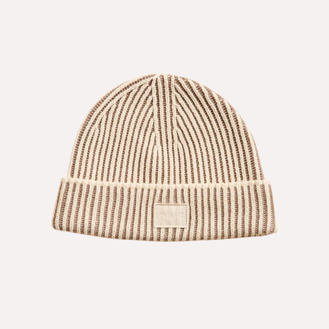 Close-up of Cyme Copenhagen's luxurious cashmere beanie in neutral tones, featuring the brand's logo, a testament to Scandinavian quality and timeless design in sustainable fashion.