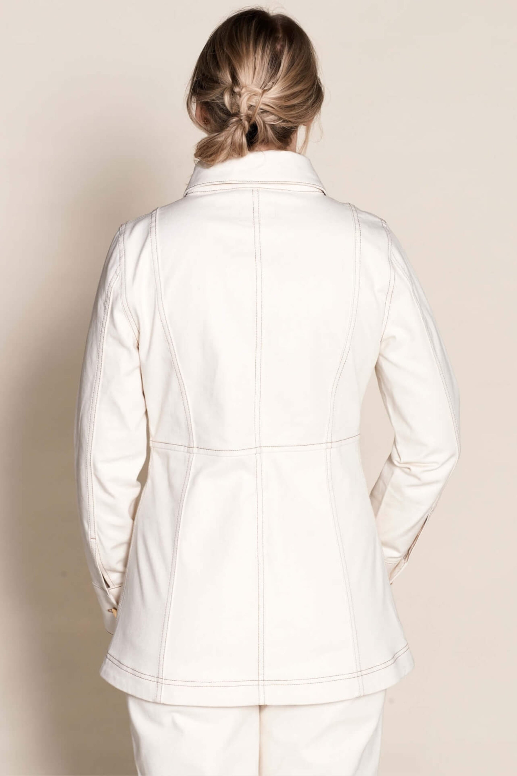 Rear view of a woman wearing Cyme Copenhagen's tailored cream denim jacket, exemplifying the brand's sleek Danish design and commitment to sustainable materials in fashion-forward women's clothing.