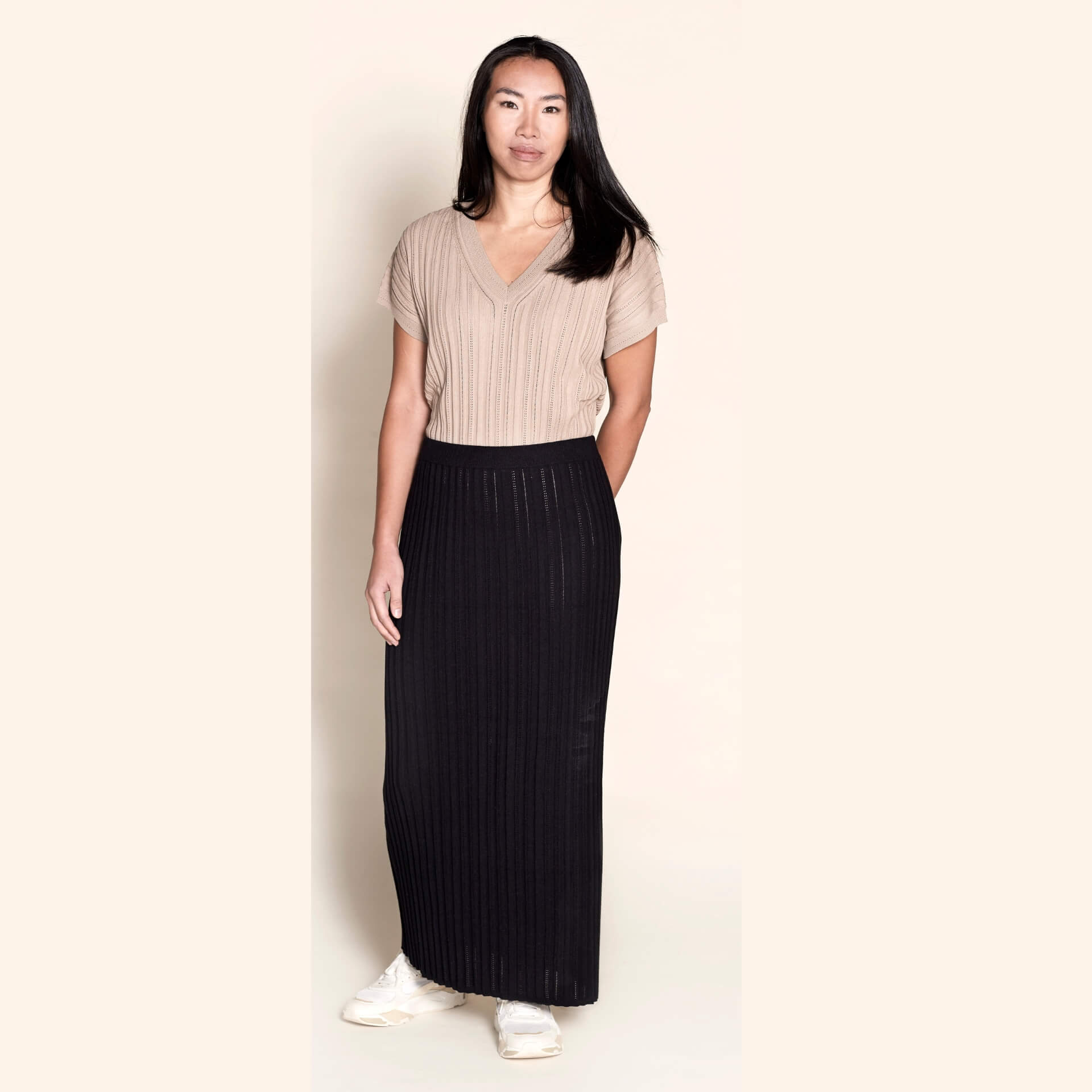 Model wearing a Cyme Copenhagen ribbed knit set featuring a taupe short-sleeved top and a contrasting black skirt, merging Danish design with sustainable fashion in a sophisticated women's clothing ensemble.