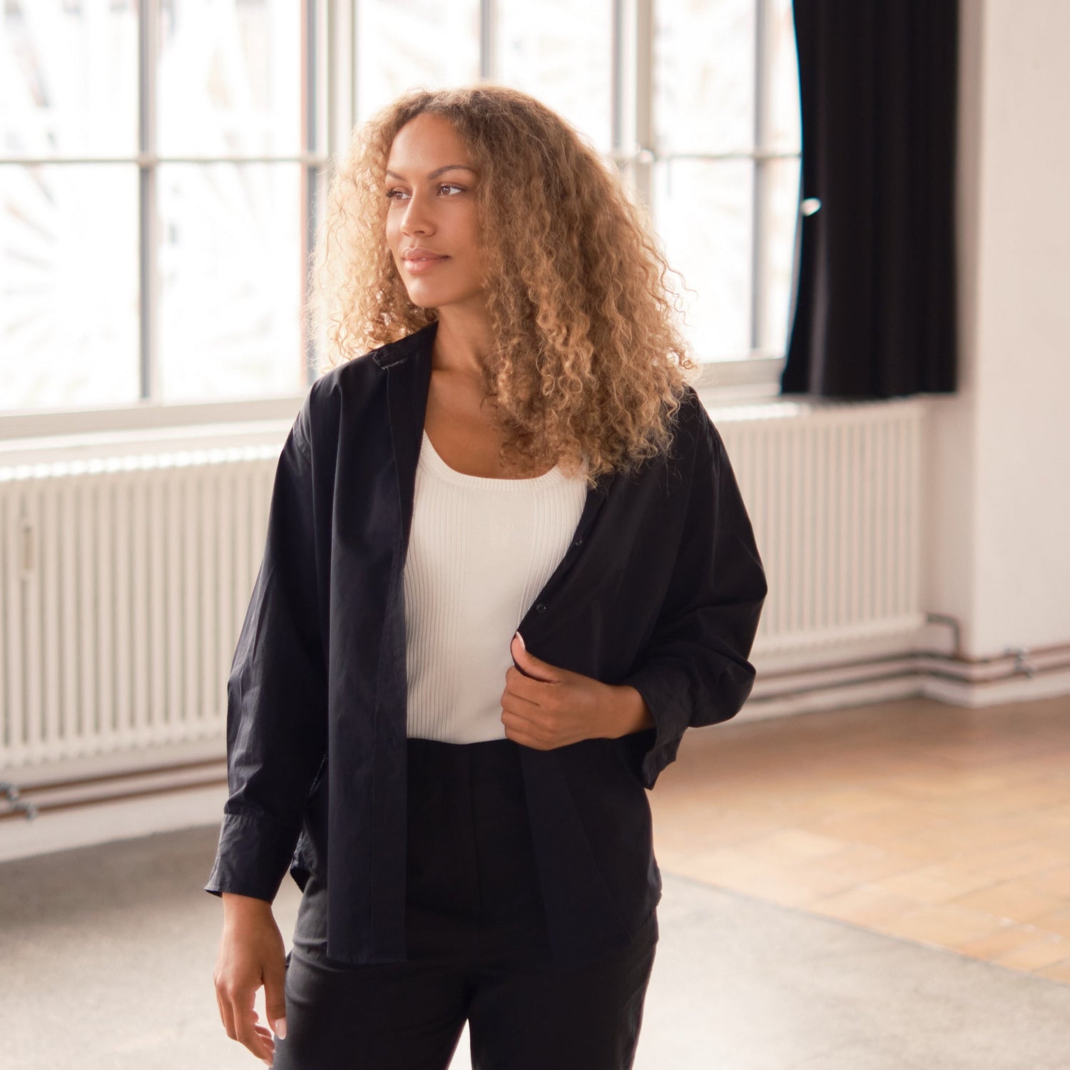 Model wearing a black shirt layered over a white top.
